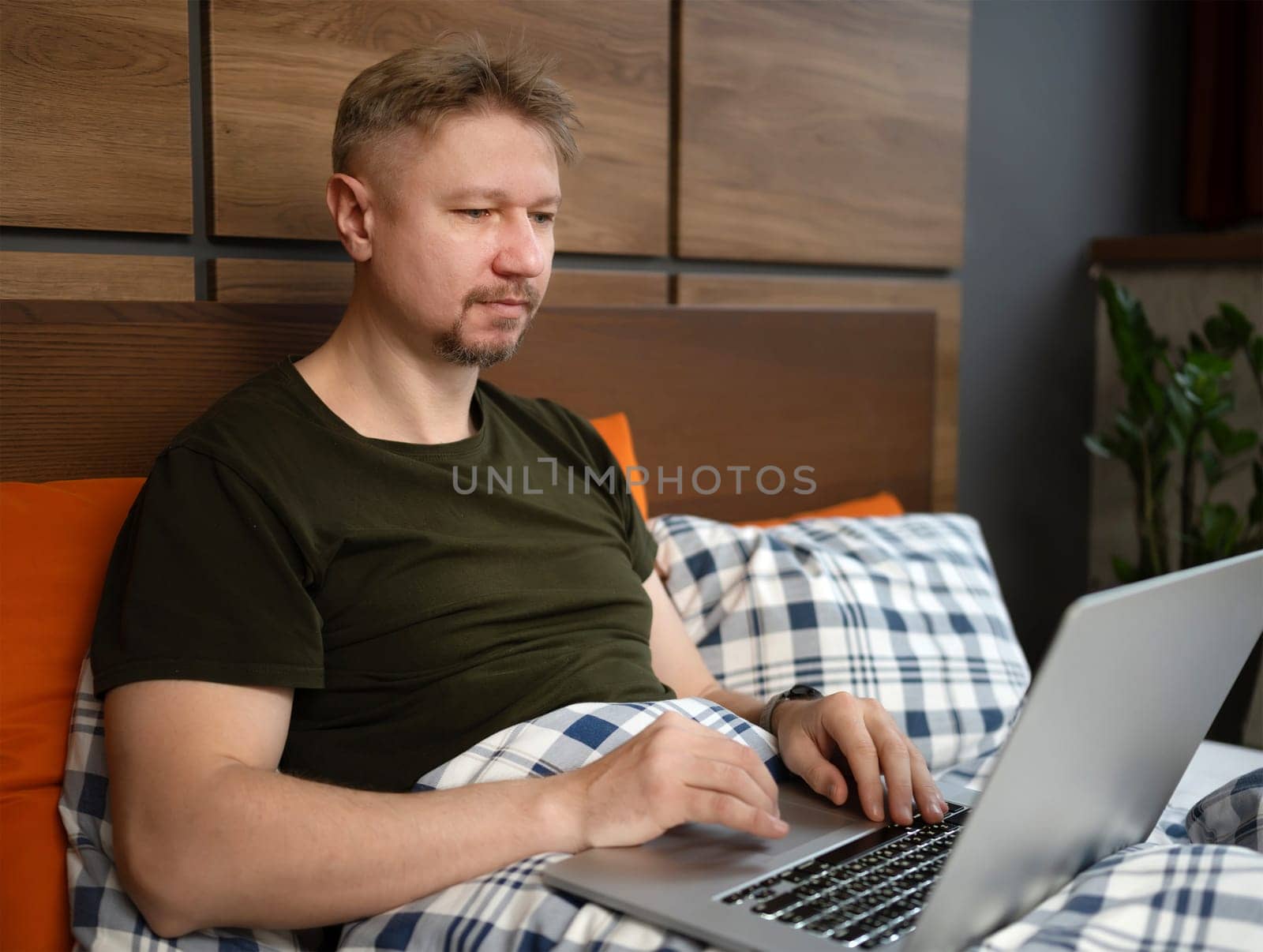 Man Watching News On Laptop In The Morning In Bed