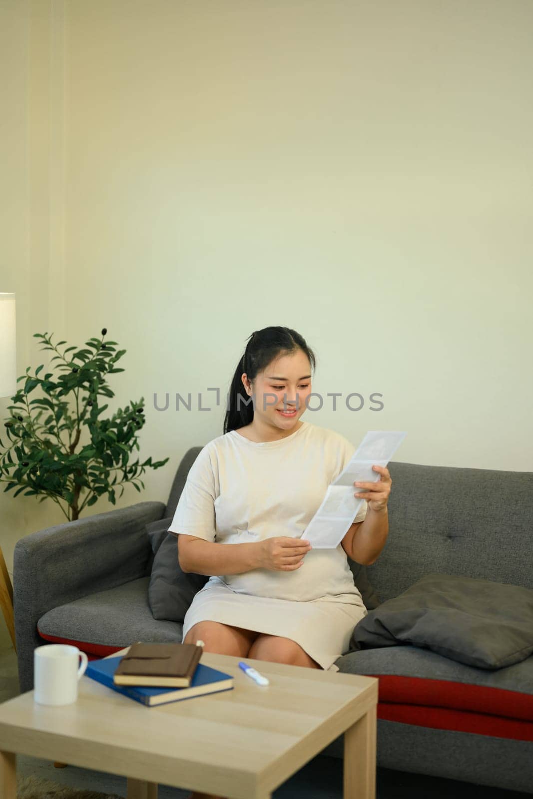 Pregnant woman lovingly admiring ultrasound while relaxing in warm and peaceful home.