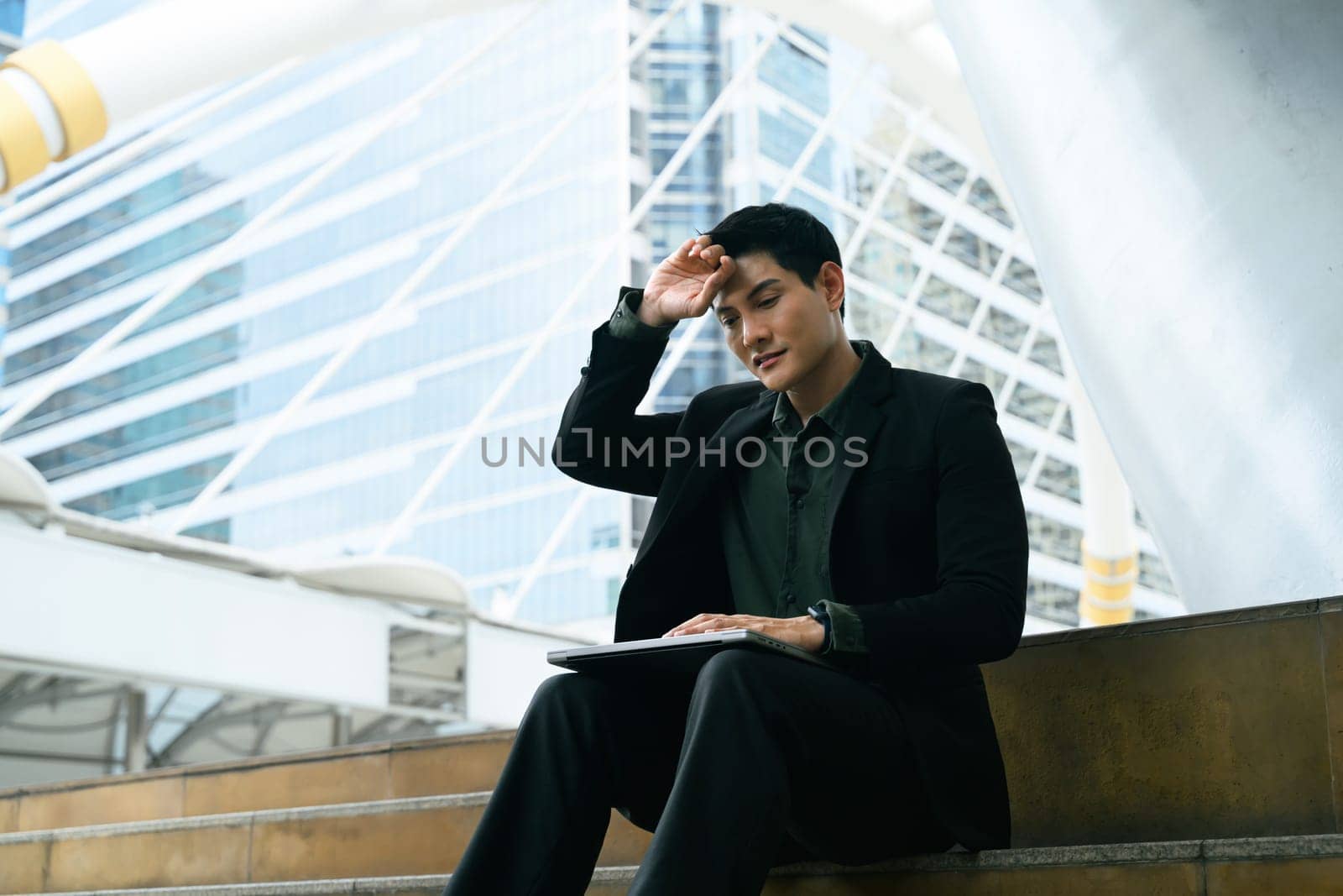 Male worker in businesswear displays signs of burnout or fatigue in an urban environment.