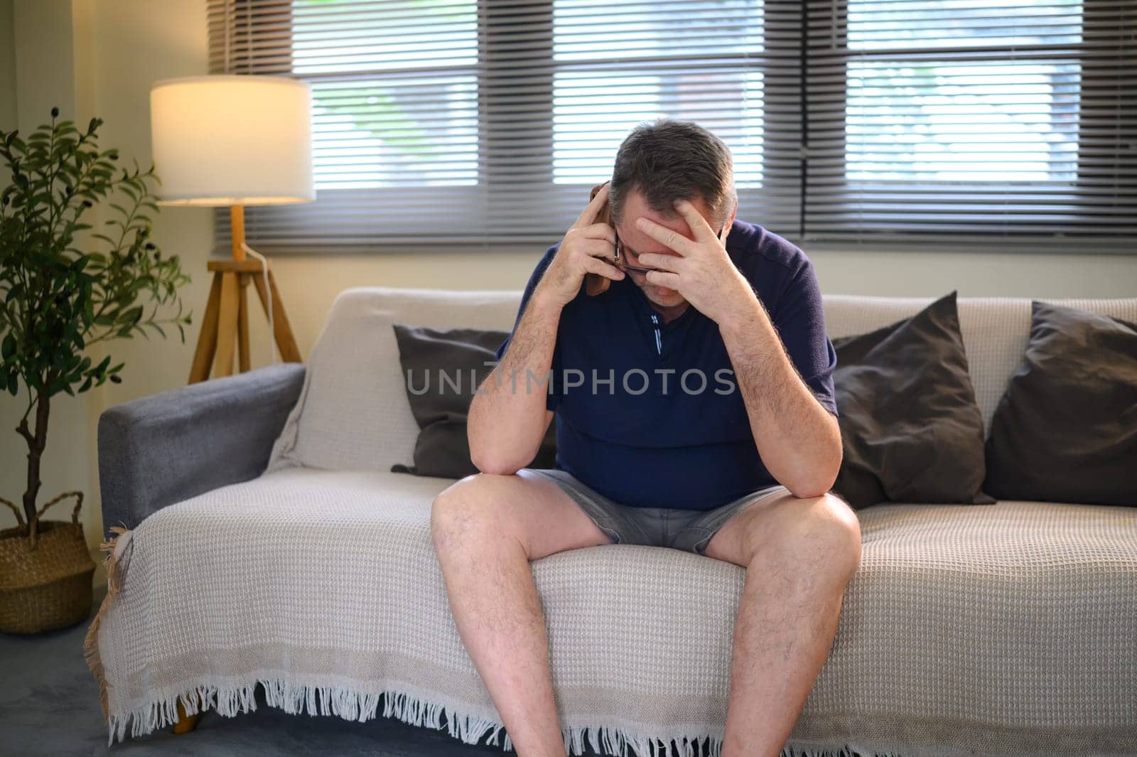 Stressed middle aged man receiving bad news over phone.
