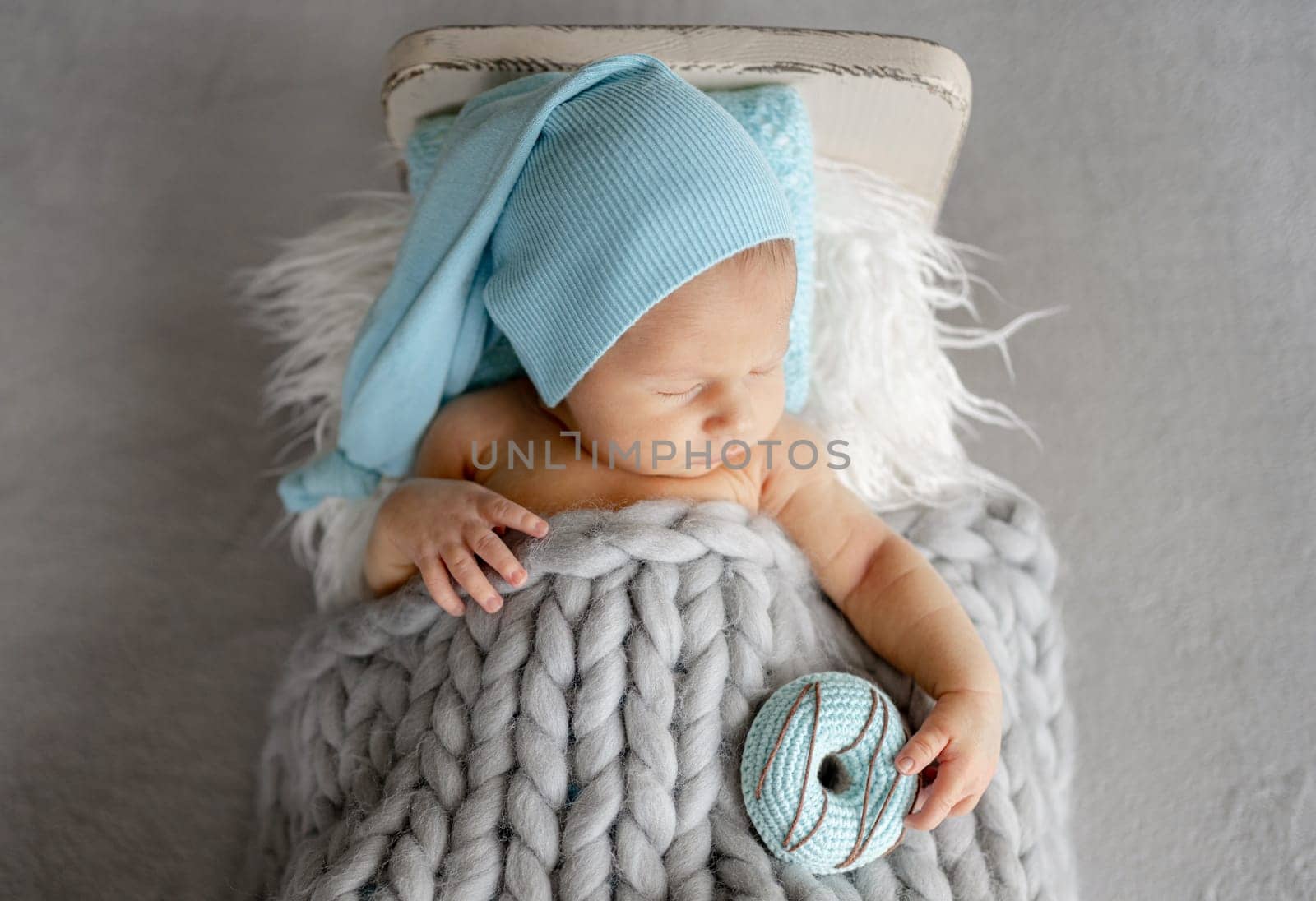 Newborn Baby Sleeping With Adorable Smile On A Little Bed In The Photo Studio