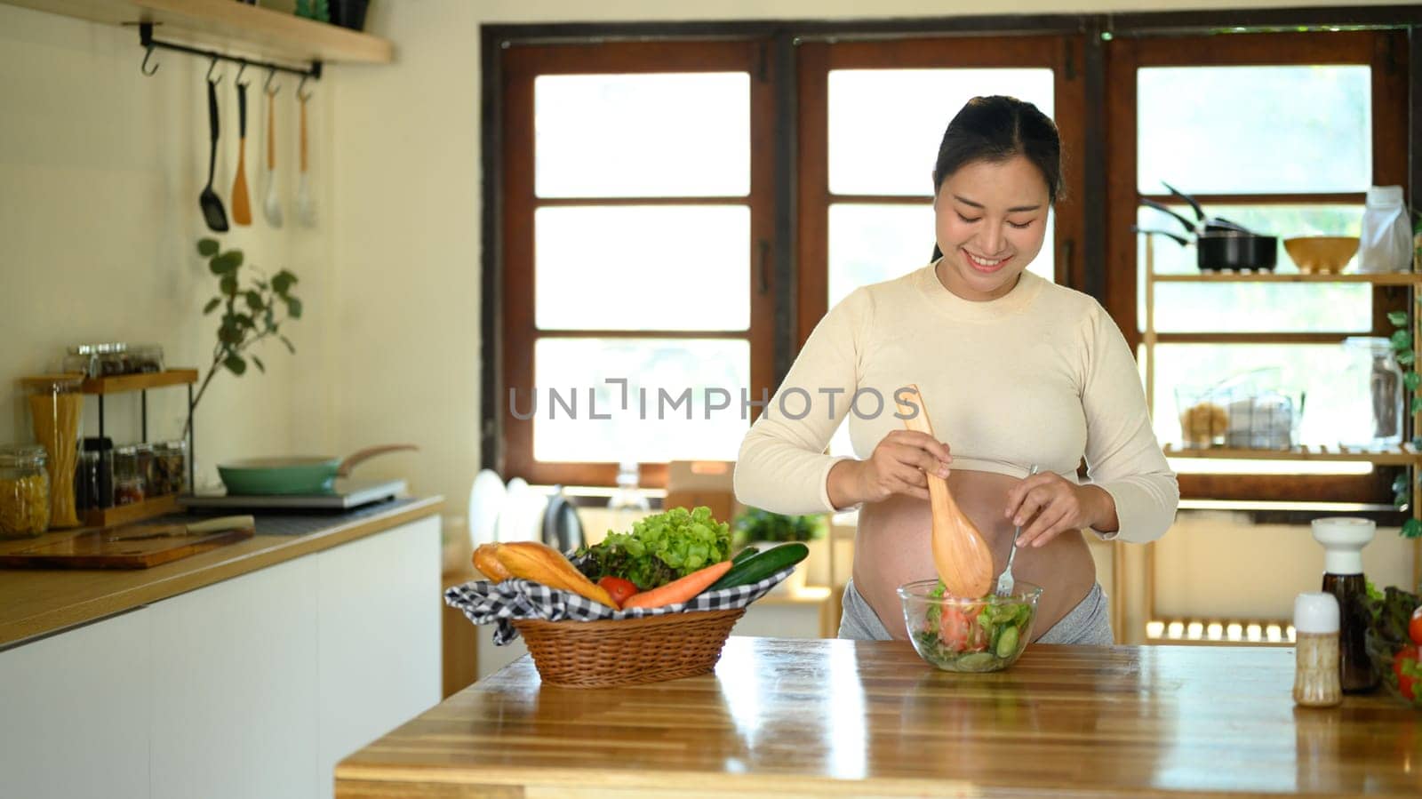 Happy pregnant woman prepares a healthy salad at home.