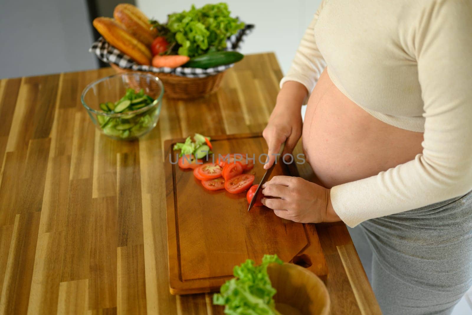Happy pregnant woman prepares a healthy salad at home.
