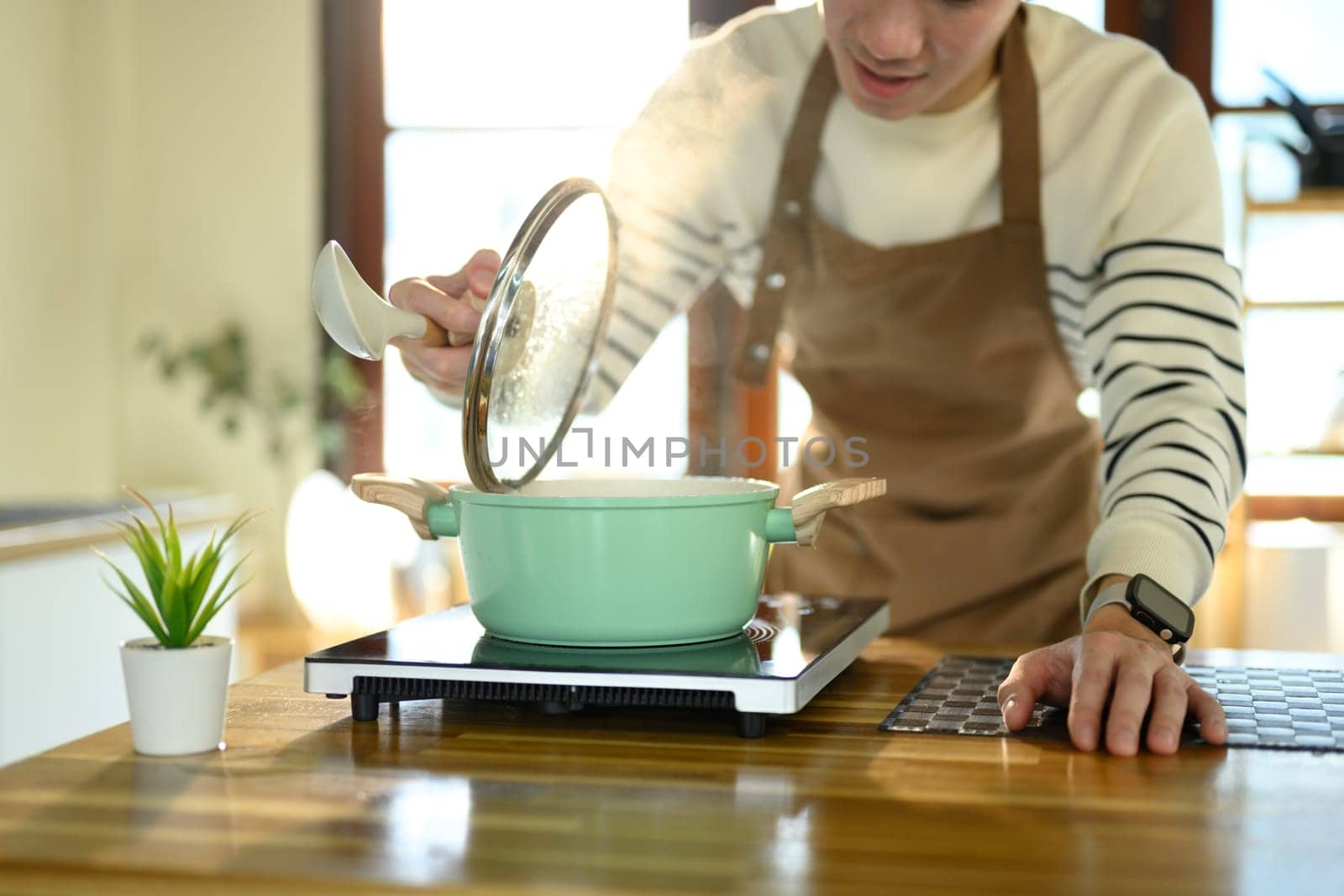 Happy Asian man cooking at home with fresh ingredients.