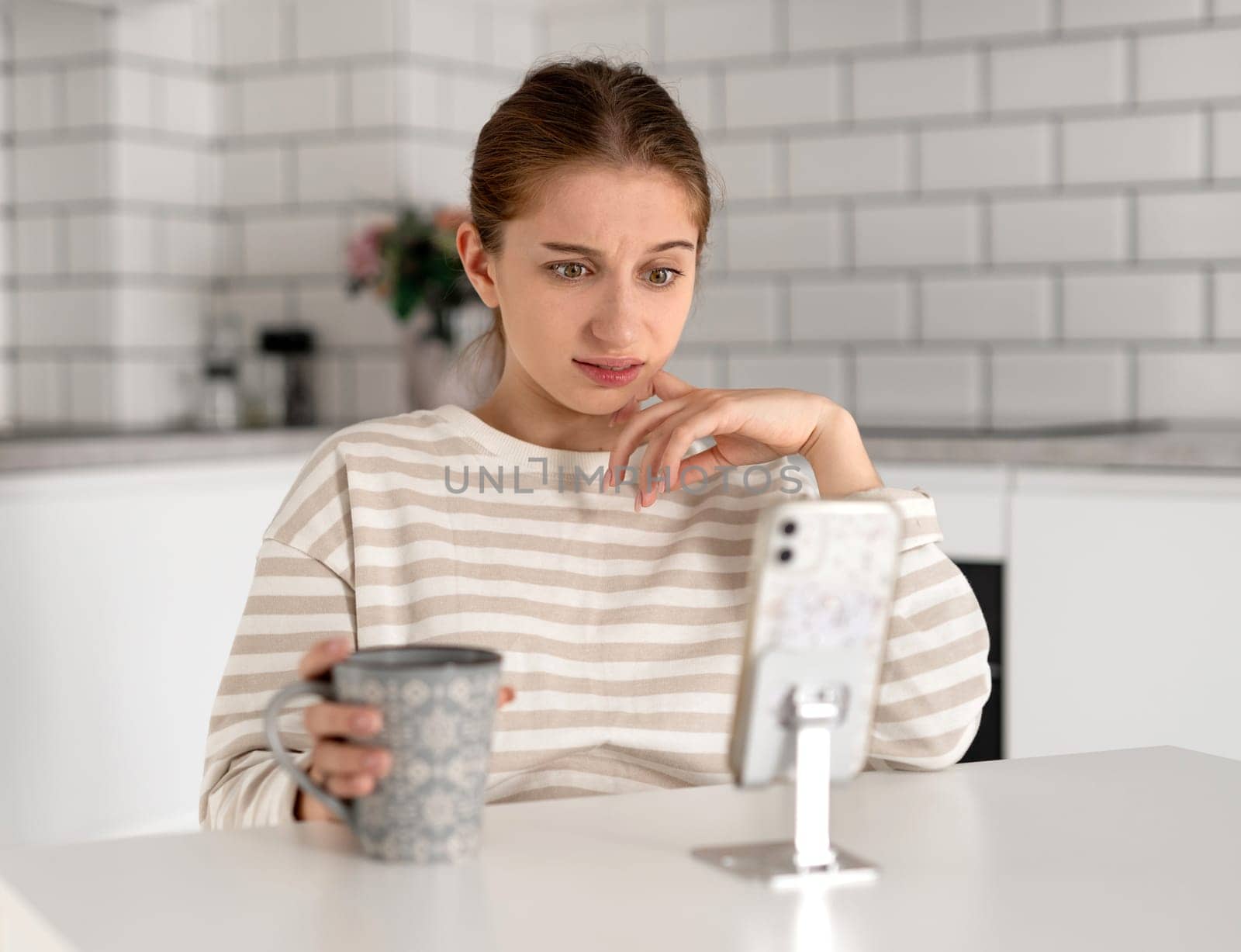 Unhappy Teen Girl Looking At Smartphone At Home