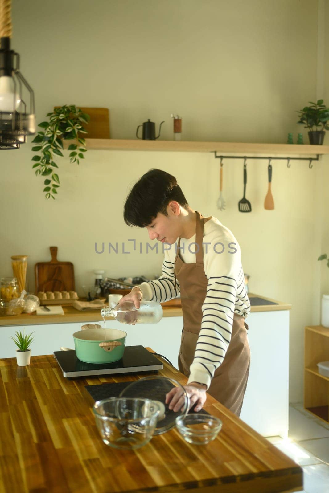Happy Asian man cooking at home with fresh ingredients.
