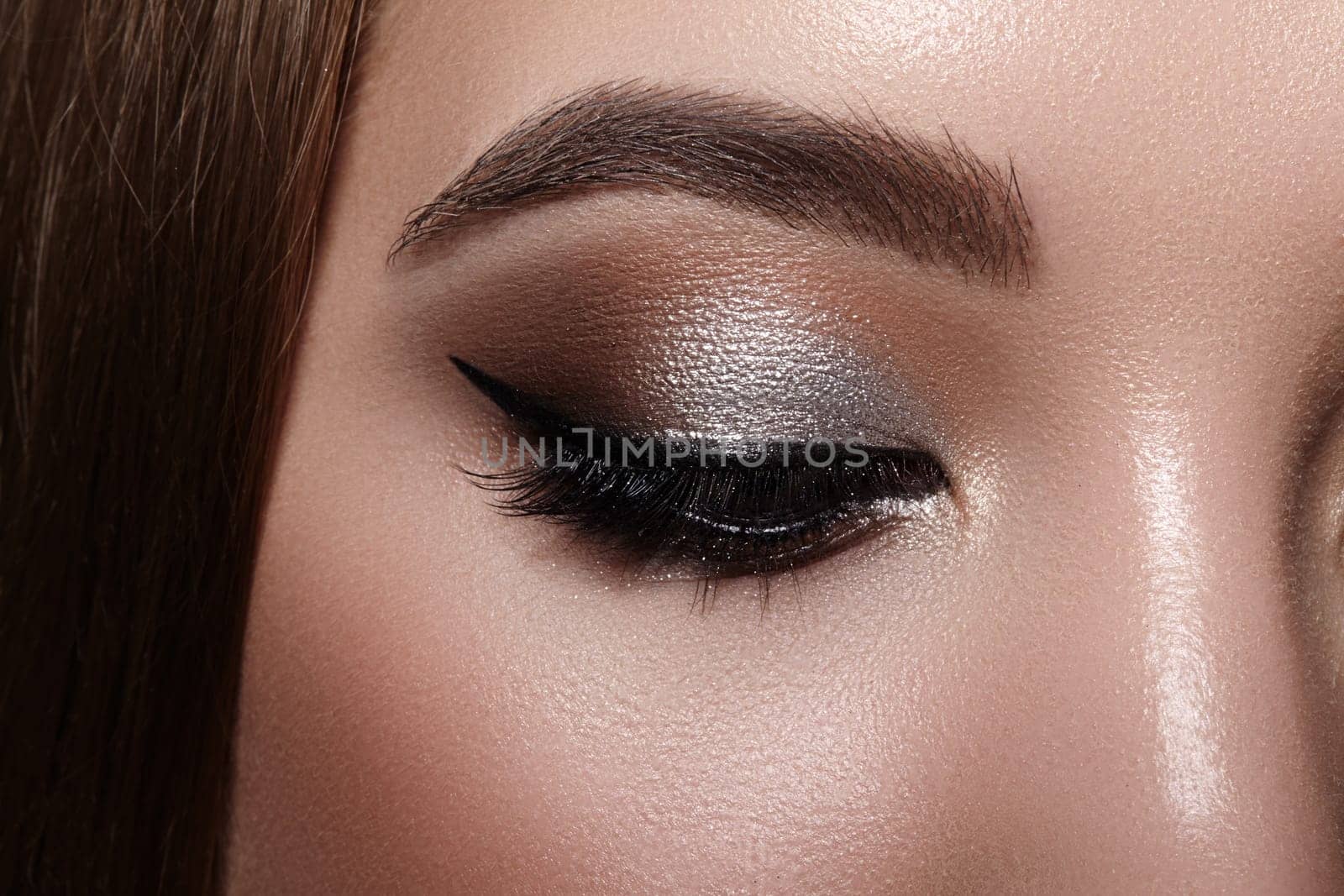 Beautiful macro shot of female eye with classic eyeliner makeup. Perfect shape of eyebrows, brown eyeshadows and long eyelashes. Cosmetics and make-up. Closeup macro shot of fashion liner eyes visage