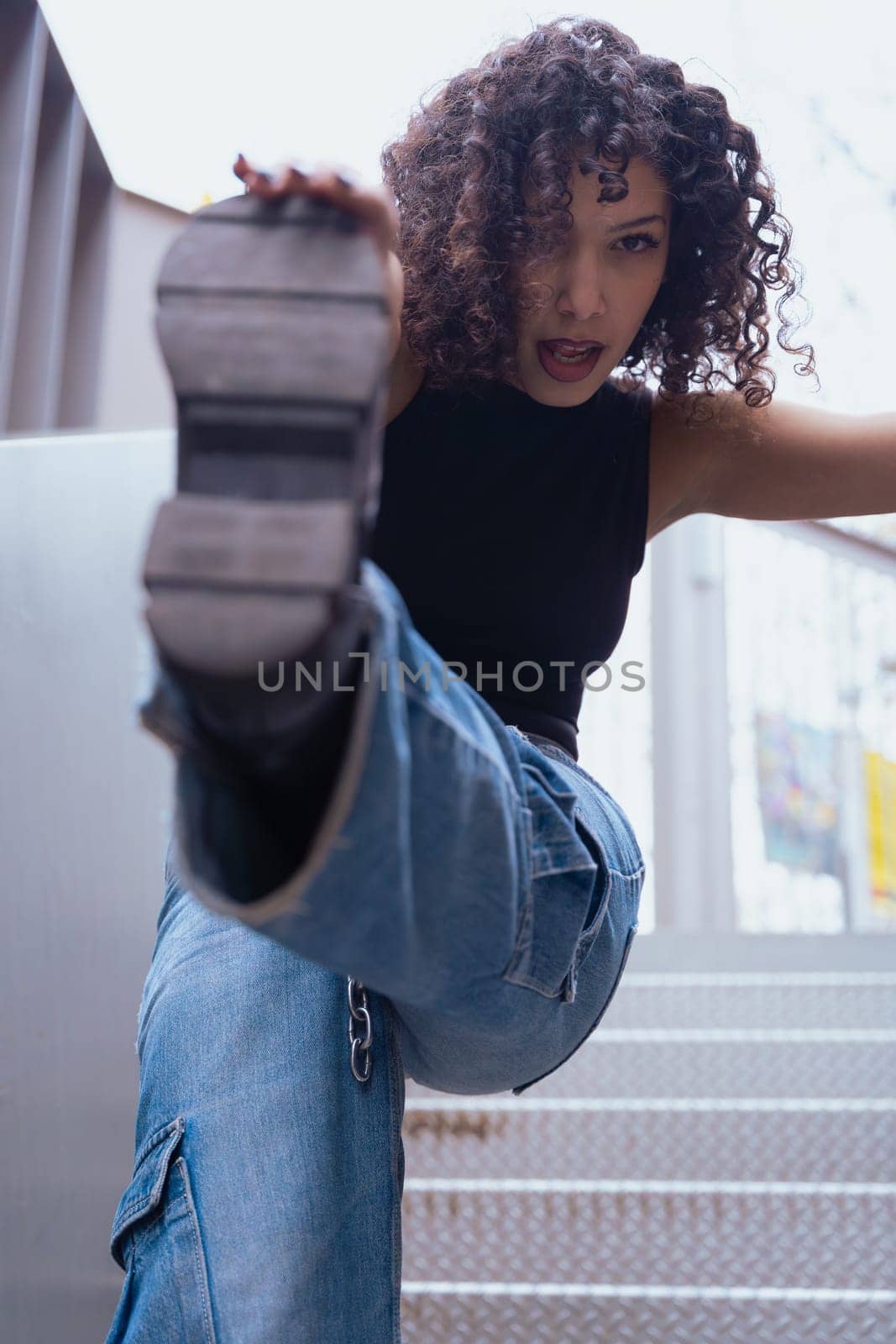African American woman dancing in a creative pose between benches in an urban setting. he wears casual clothes and shows balance,strength, and expression. Concept of movement, art,and freedom.Vertical