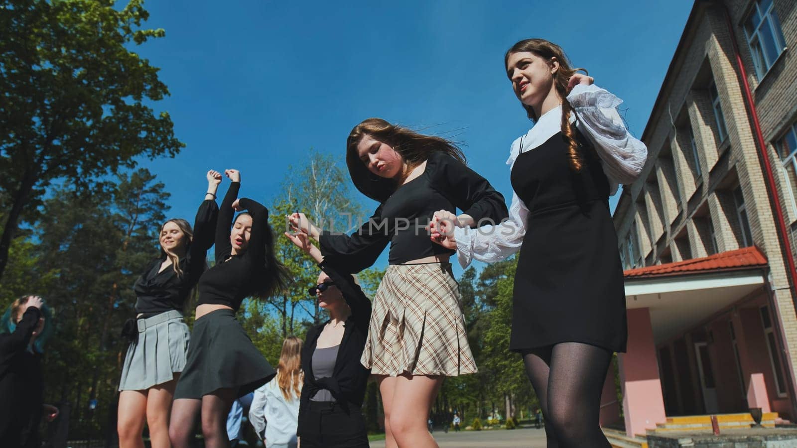 Group of happy high school students dancing and celebrating their graduation day outdoors, enjoying their achievement and freedom