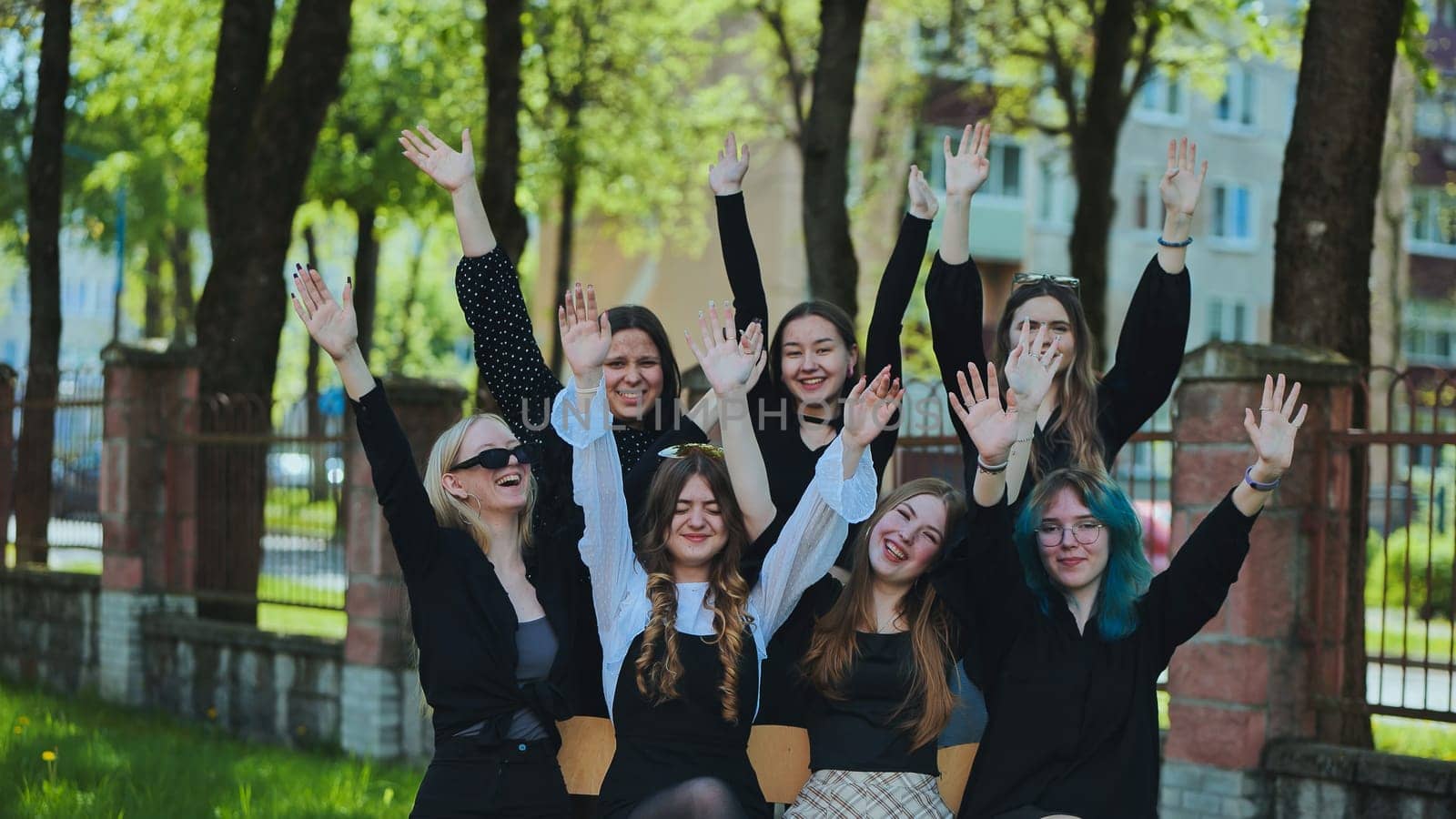 Group of cheerful students raising their hands outdoors, celebrating the end of school day