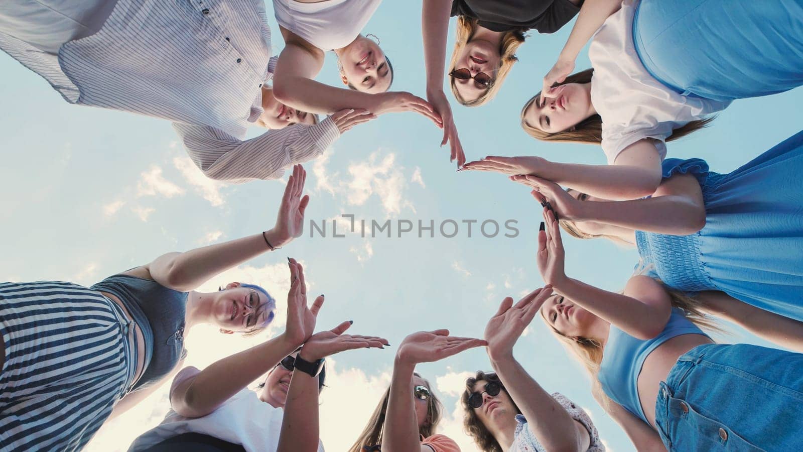 Group of school friends forming a circle with their hands, symbolizing unity, teamwork, and friendship against a cloudy sky
