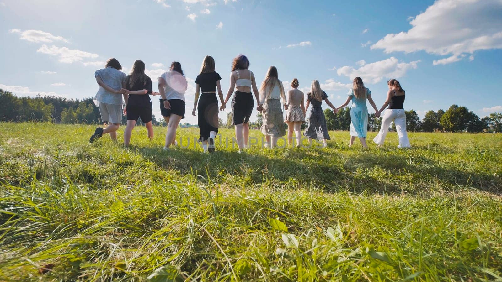 Group of high school students walking together in a field holding hands, enjoying their summer break