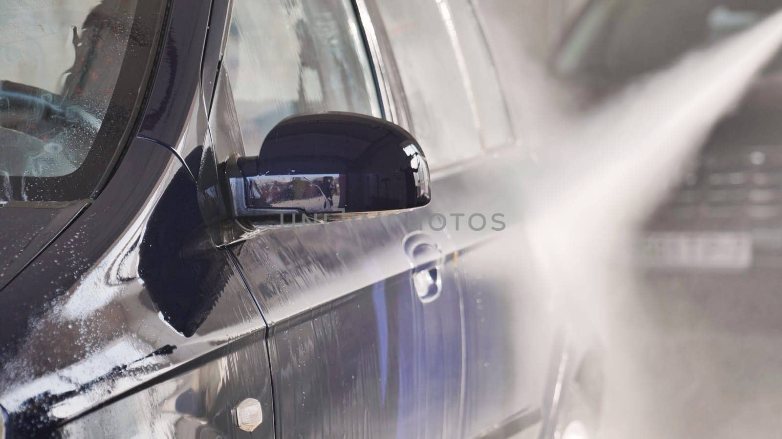 High pressure water jet cleaning a car at car wash