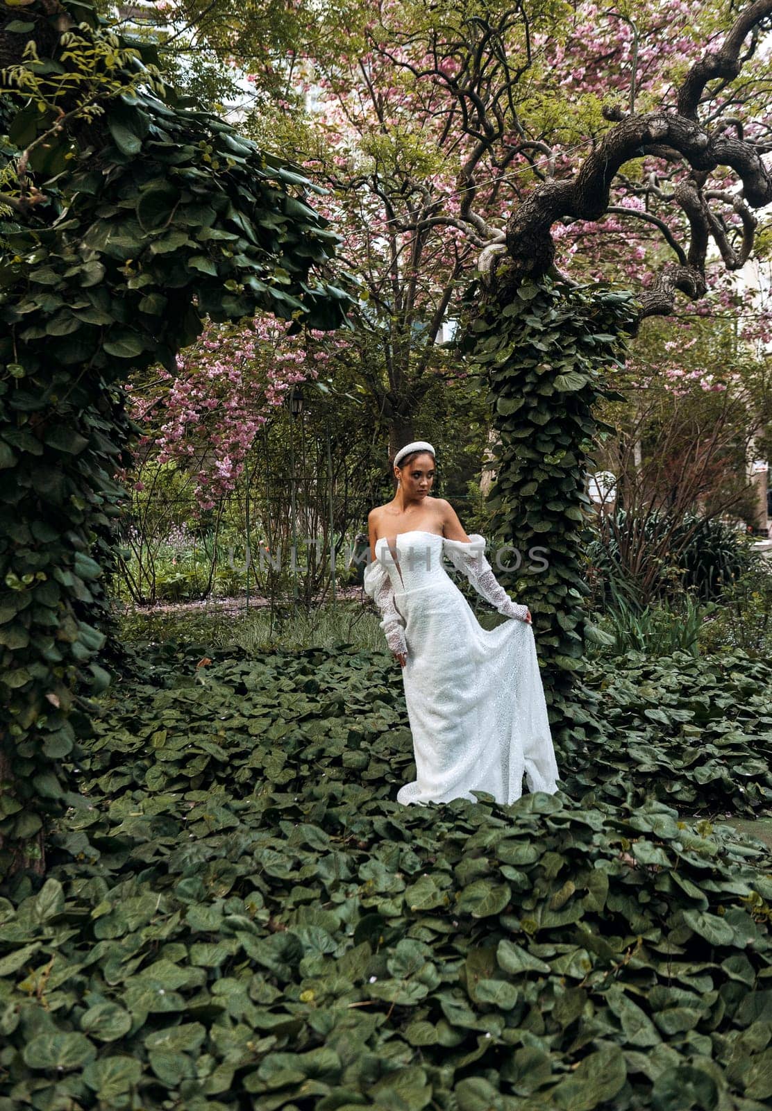 Beautiful bride in lace dress is smiling against the background of nature and green trees. Portrait of a young bride. Wedding photography. High quality photo