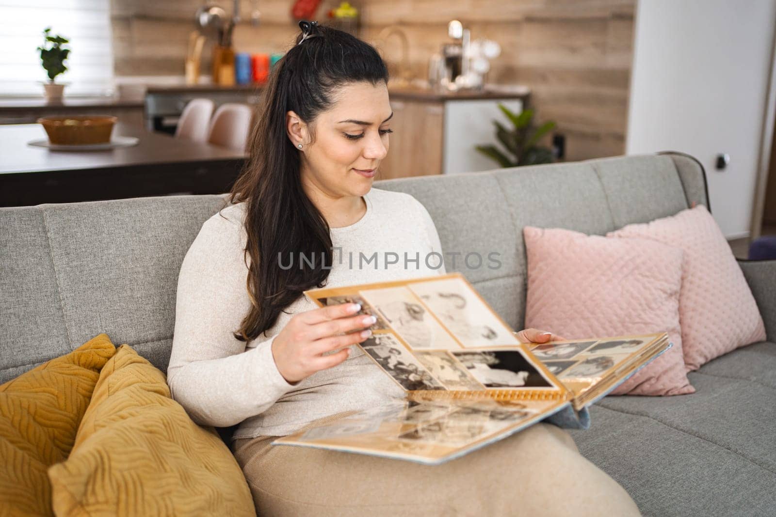 Woman looking at a photo album while relaxing on a sofa at home.