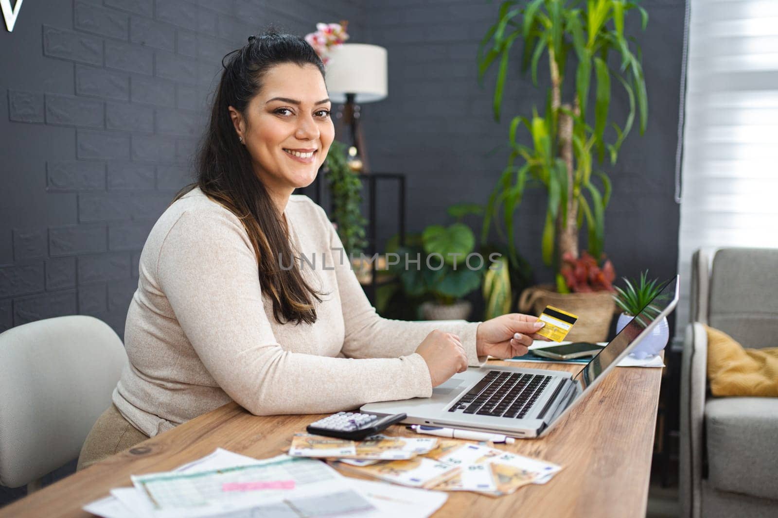 Smiling woman online shopping on laptop at home.