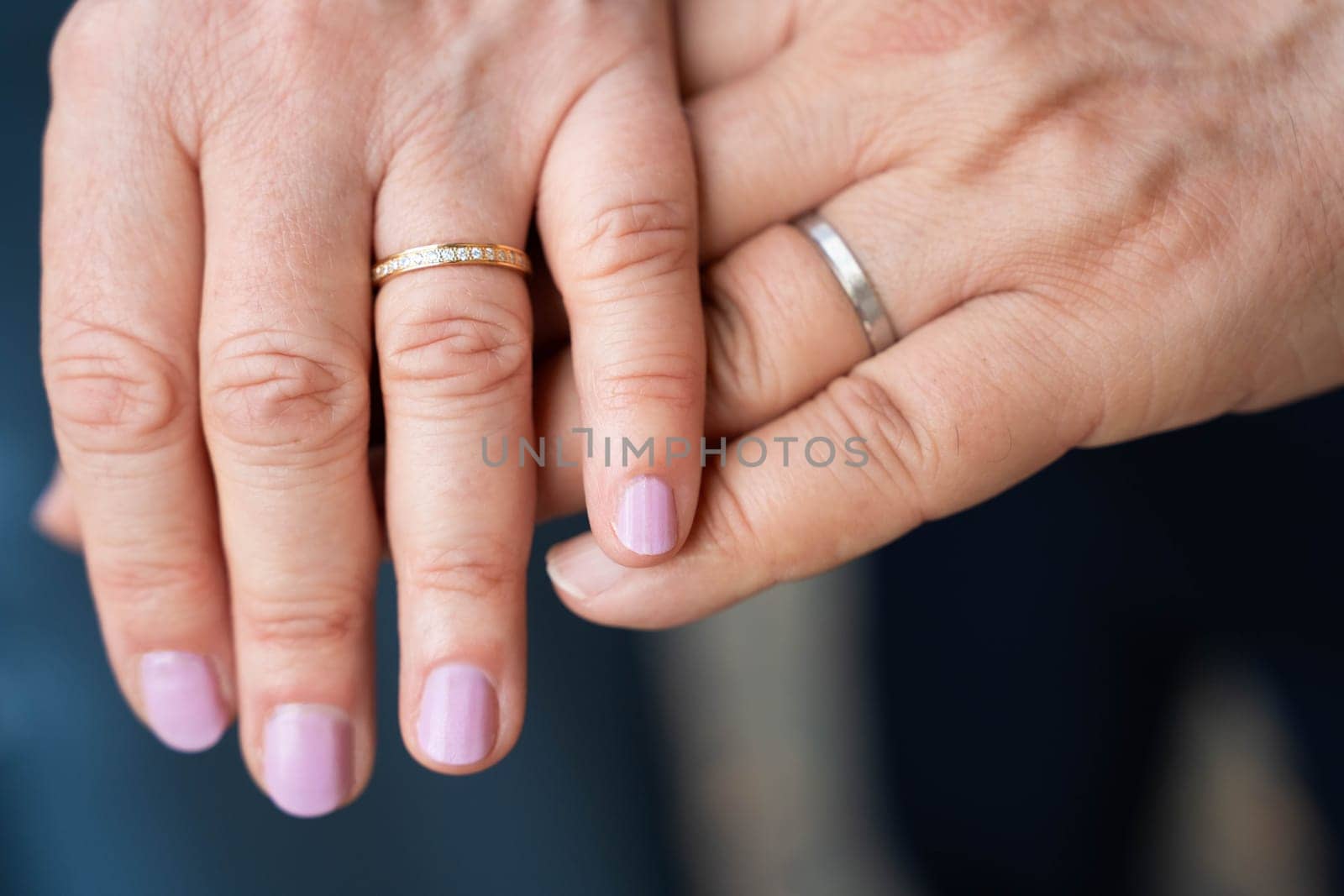 Married elderly couple holding hands with rings wedding day