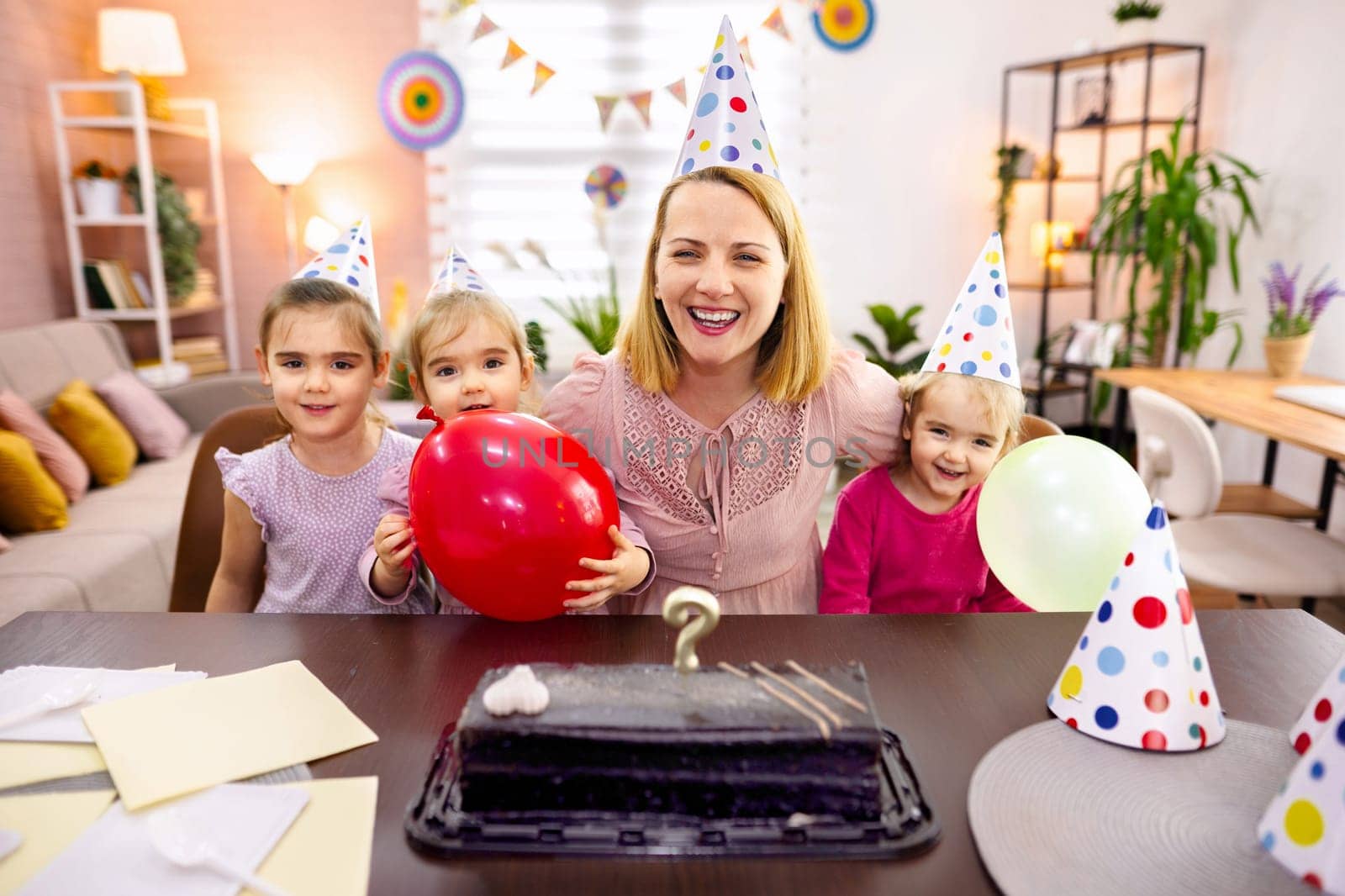 A woman and children share laughter at a festive birthday gathering.