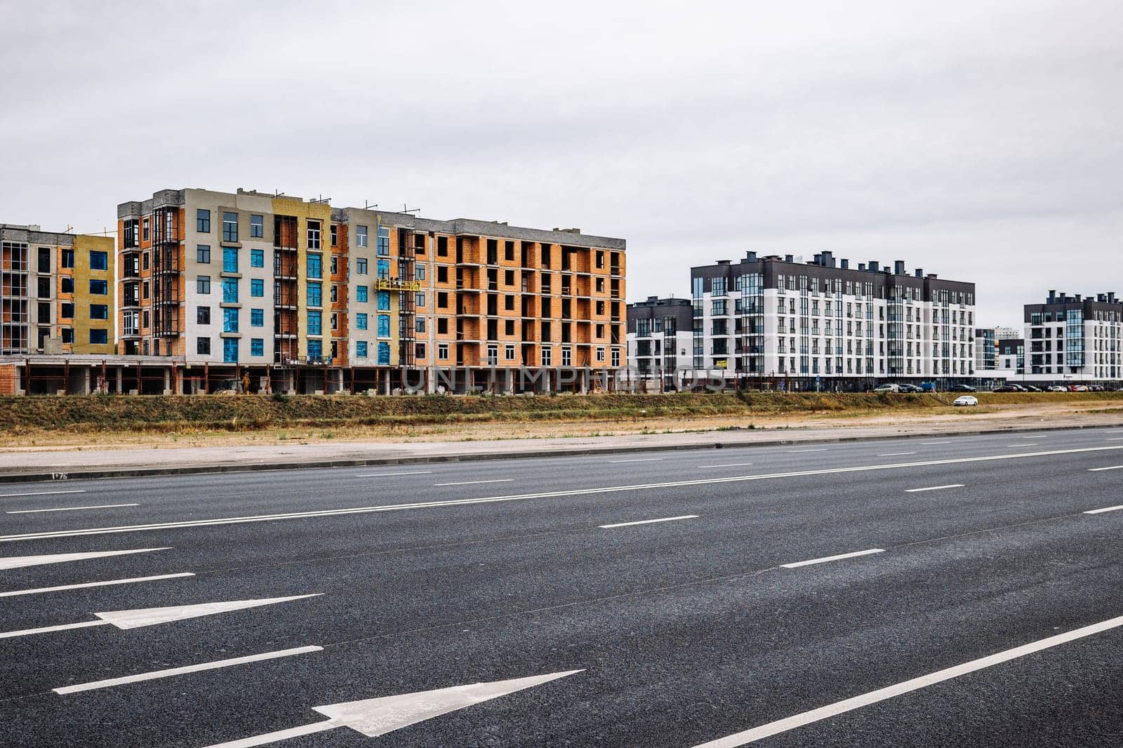 Construction site of new apartment buildings near asphalt road with white arrows