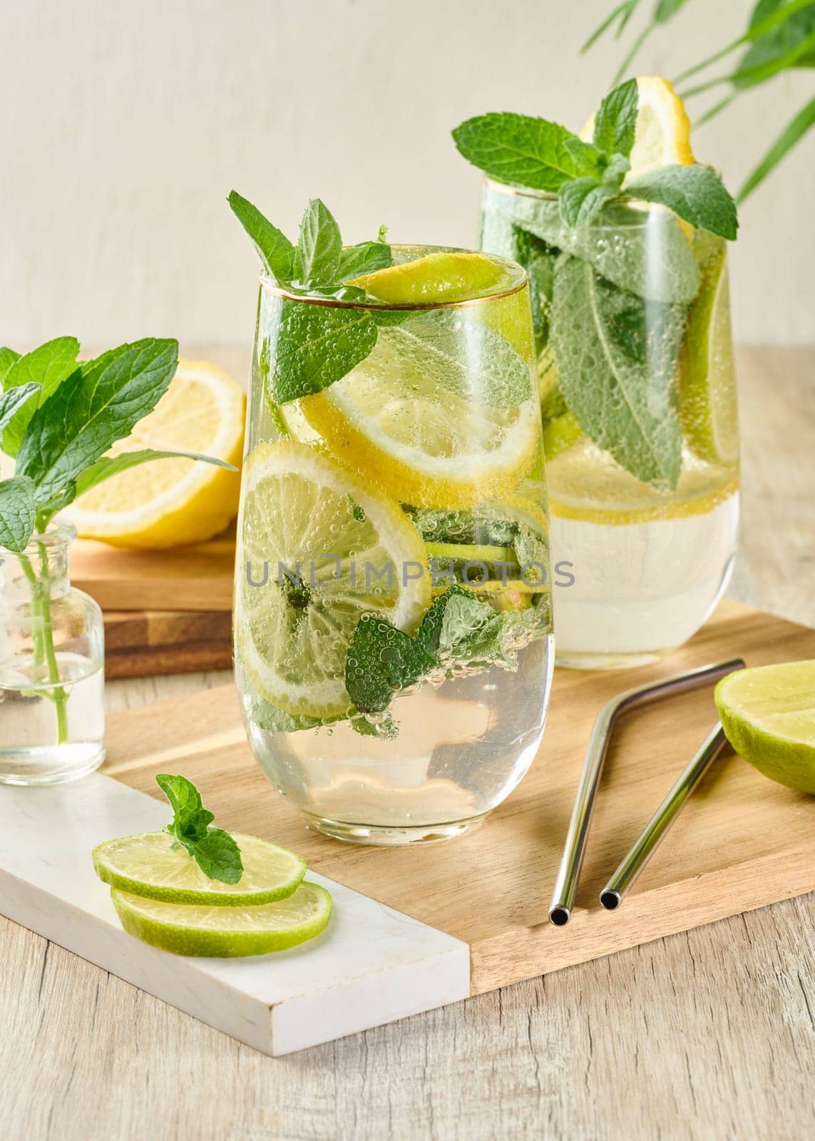 Refreshing citrus and mint drink in glasses with ice, lemon, lime, and mint leaves. Healthy summer beverage