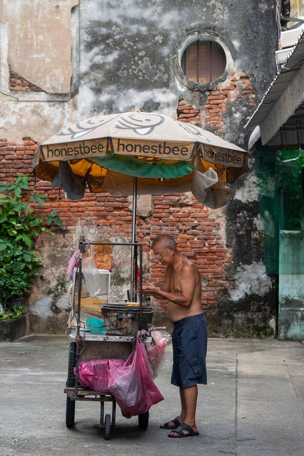 a old men on a grill in alley in Talat Noi at China Town in City of Bangkok in Thailand.  Thailand, Bangkok, November, 5, 2024.