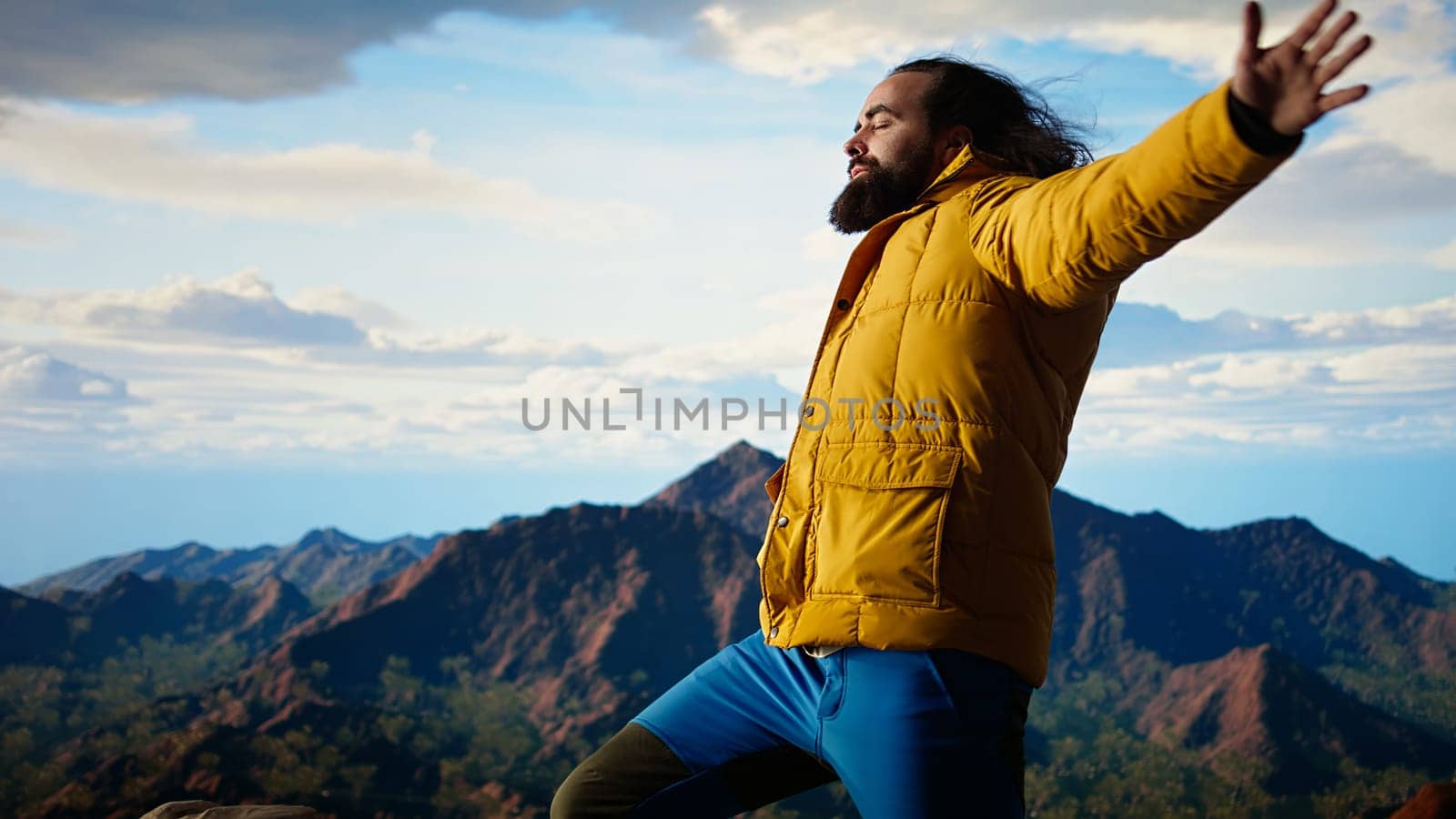 Happy adventurer embraces the thrill of standing at the top of the mountain, feeling the power of accomplishment. Awe inspiring mountain range with peaceful sky and vast wilderness. Camera A.