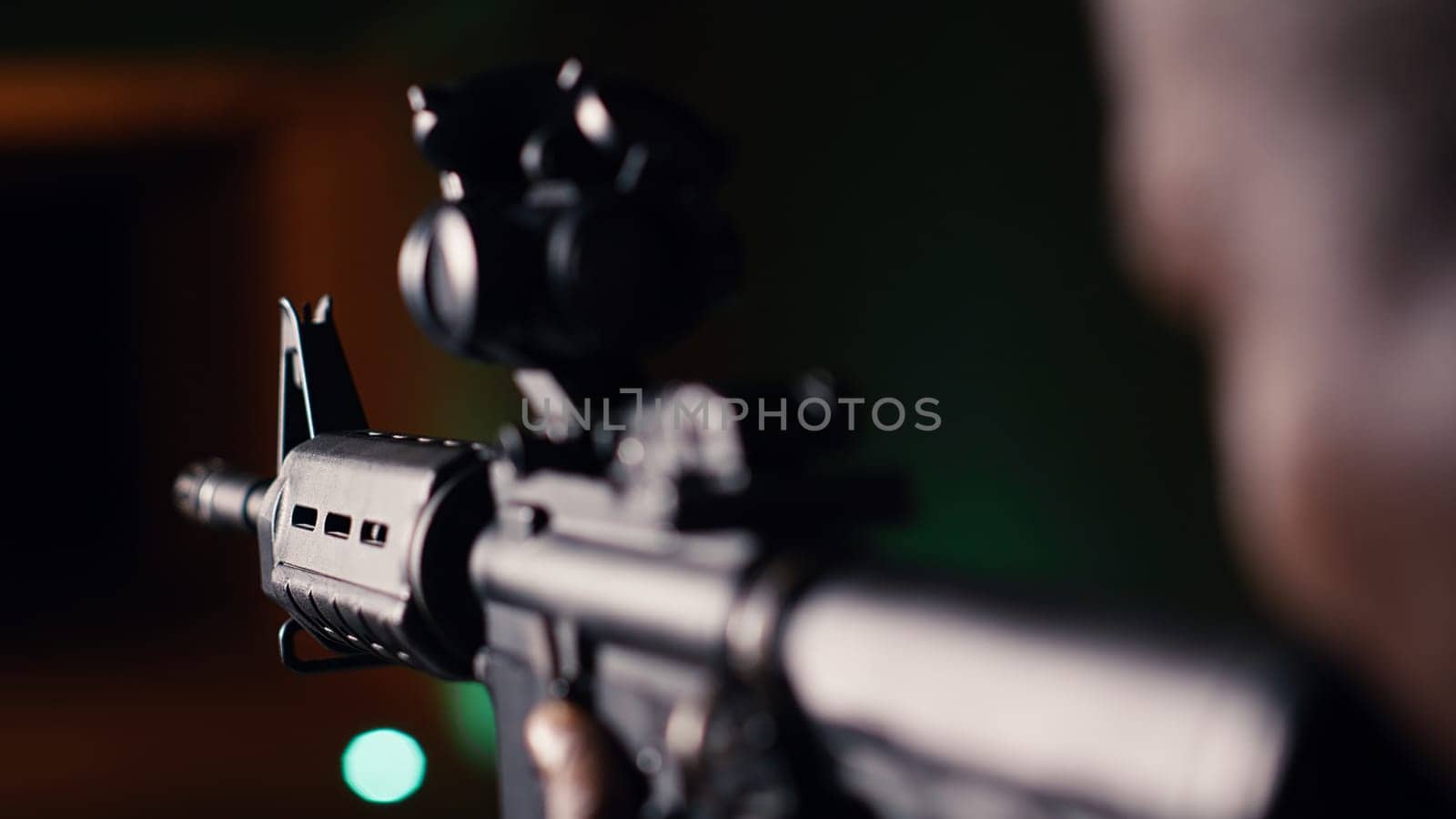 Man holds assault rifle, enjoying recreational shooting experience in firing range. Person practices with semiautomatic weapon in safe environment at shooting range company, camera B extreme close up