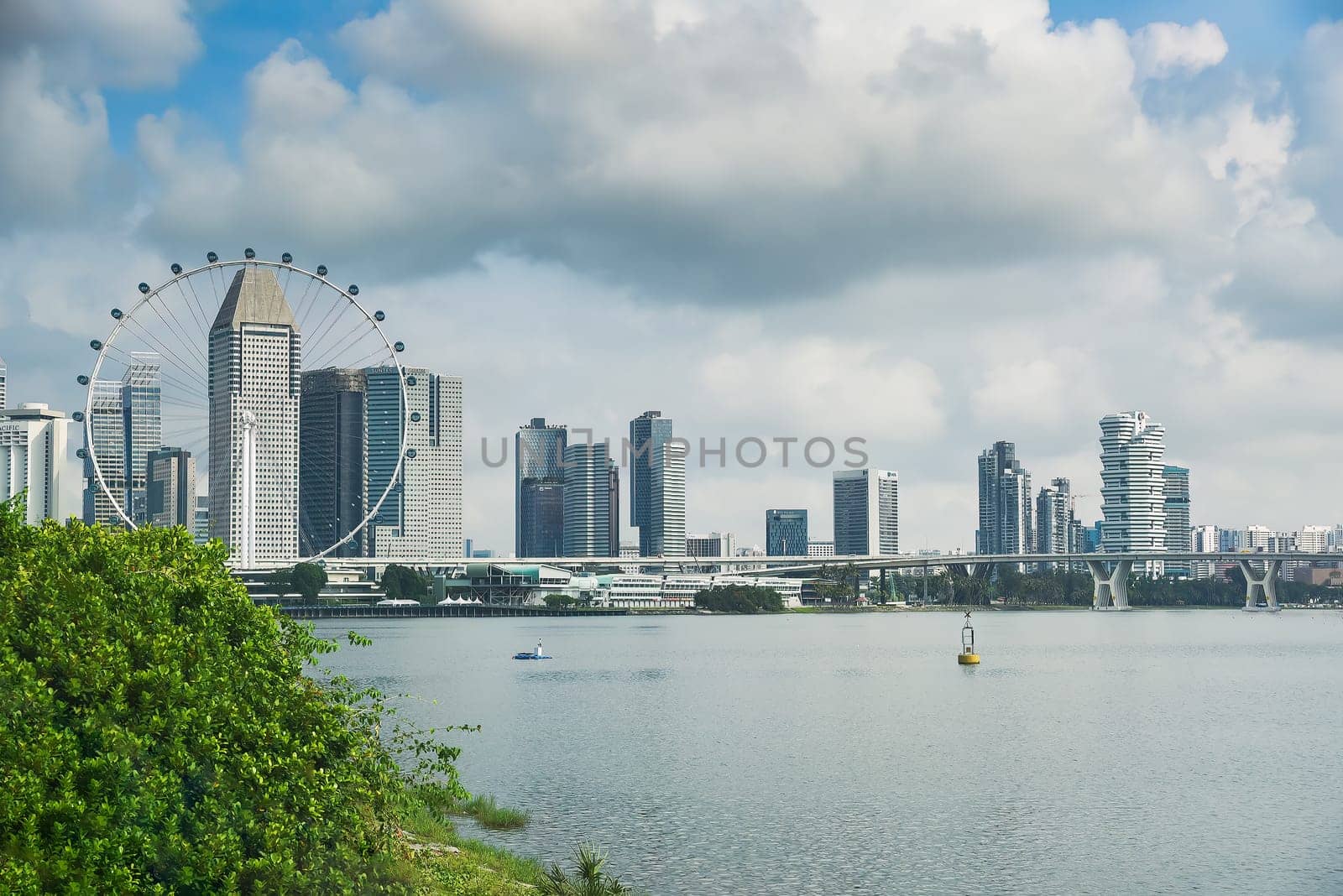 Singapore, Singapore - 4 April 2025: City skyline view with Singapore Flyer and modern buildings near the bay under cloudy sky, seen from Marina Bay area.