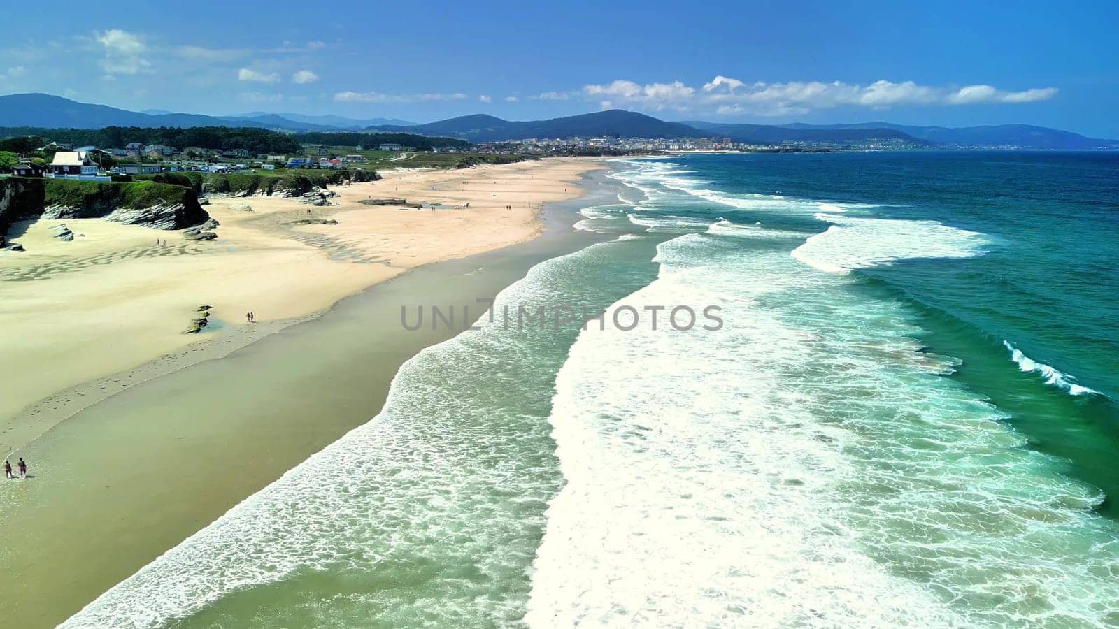 An absolutely breathtaking coastal view highlighting rolling waves, sandy shorelines, and a clear blue sky