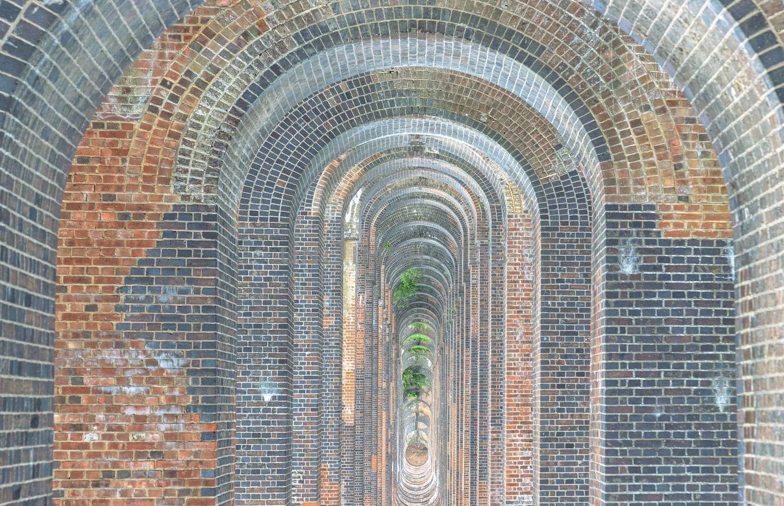 Sussex, UK - May 21, 2025 - The semi-circular arches vaulting supporting brick piers, composed of traditional red bricks topped with smooth limestone and has been described as “the most elegant viaduct in Britain”. Ouse Valley Viaduct or Balcombe Viaduct (Railway viaduct) carries the Brighton Main Line over the River Ouse in Sussex. use it as your Wallpaper, Poster and Space for text, Selective focus.