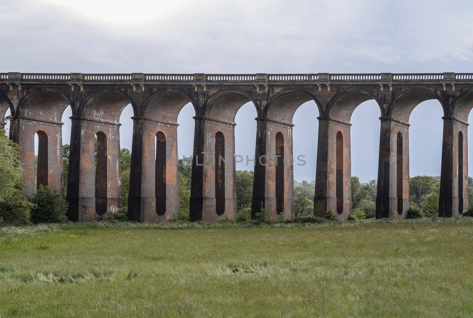 Sussex, UK - May 21, 2025 - Architectural splendour of Ouse Valley Viaduct or Balcombe Viaduct (Railway viaduct) with sky background, carries the Brighton Main Line over the River Ouse in Sussex, has been described as “the most elegant viaduct in Britain”, The semi-circular arches vaulting supporting brick piers, composed of traditional red bricks topped with smooth limestone. use it as your Wallpaper, Poster and Copy space, Selective focus.