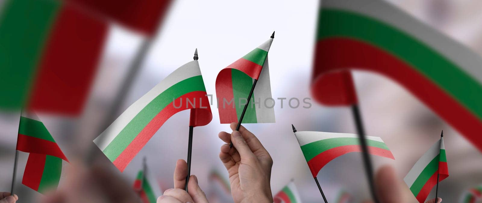 Bulgaria flags in their hands on a blurred urban background. The photo illustration was created without the use of artificial intelligence, only using Photoshop.