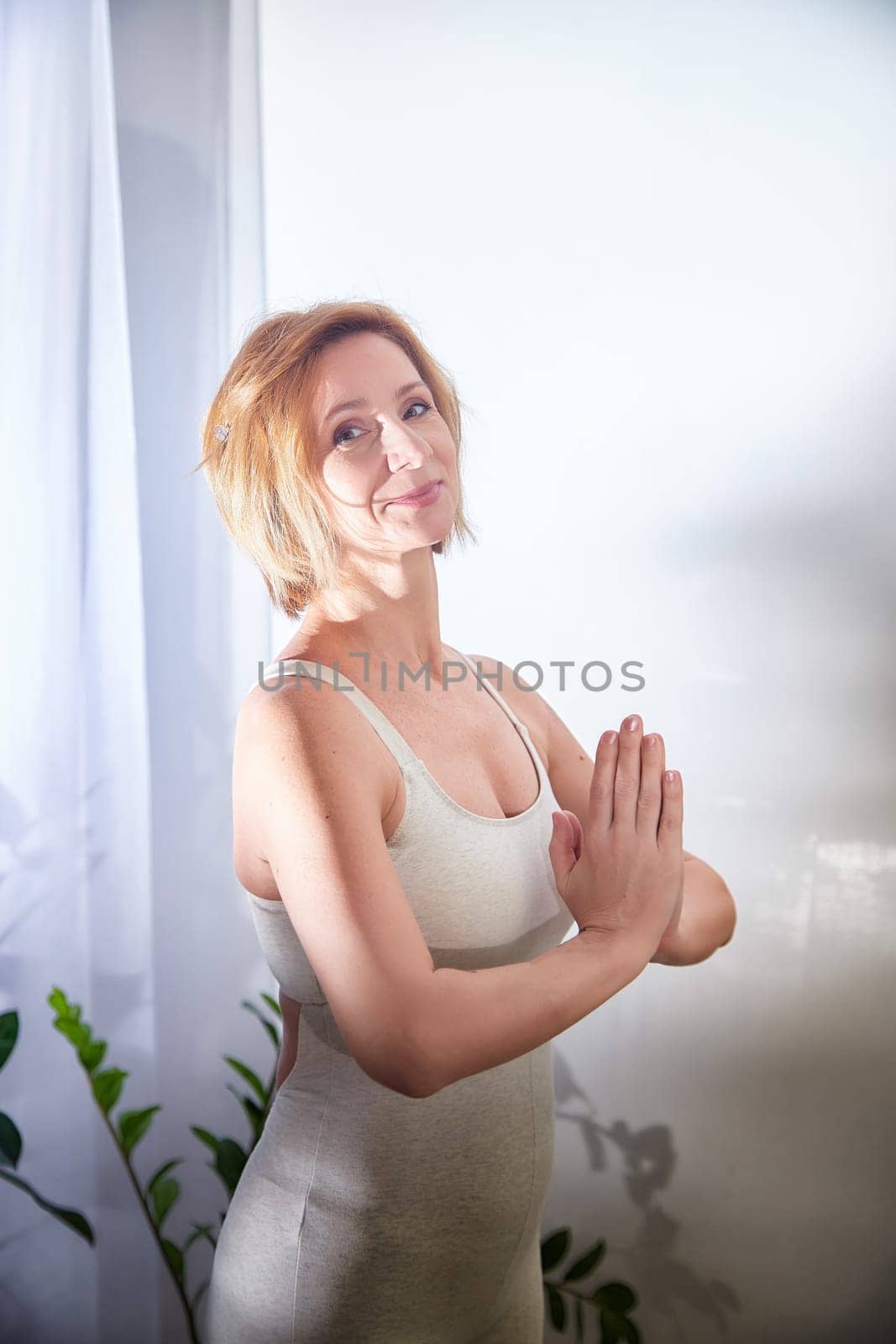 A woman practices yoga in a peaceful space, surrounded by natural light and greenery, showcasing a commitment to a healthy lifestyle.