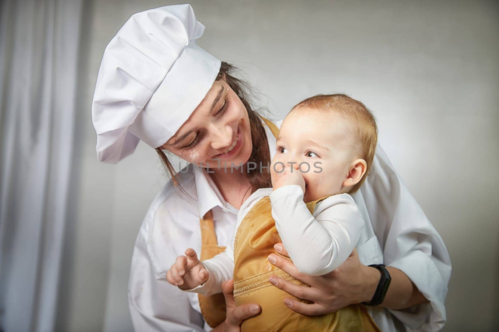 A family enjoys a fun cooking session, playfully covered in flour while engaging with their little ones in warm kitchen. Mother and son having fun