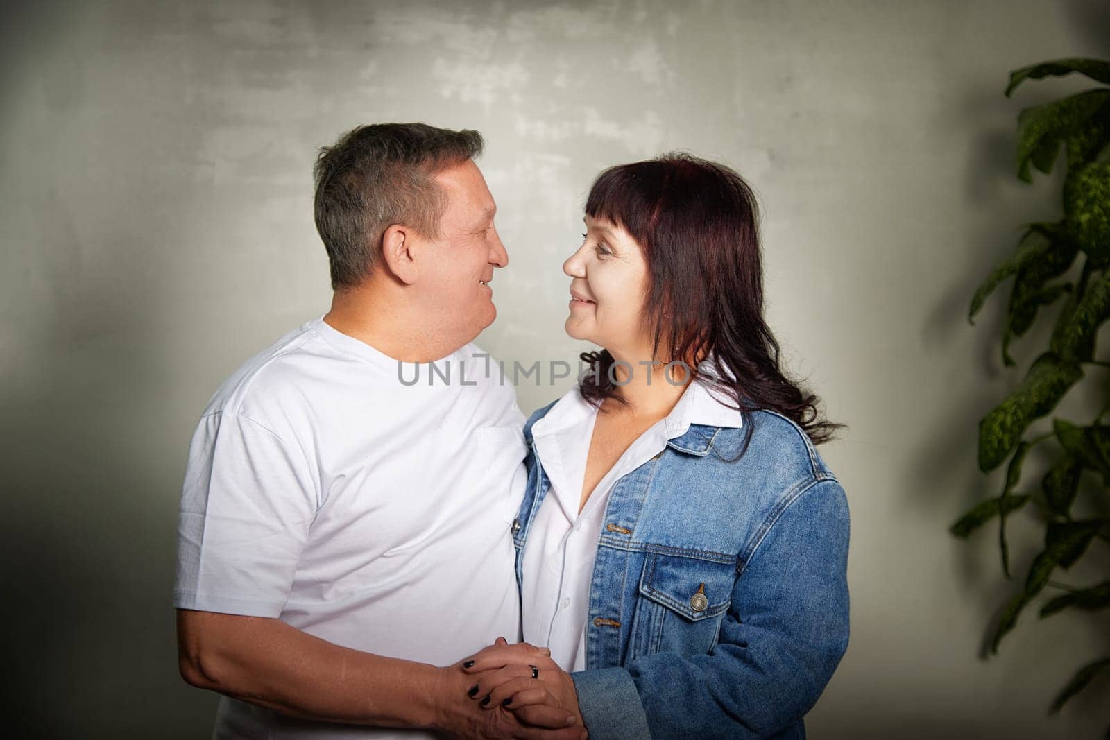 Middle-aged couple poses together in their apartment, enjoying a loving moment while capturing their bond during a fun photo shoot.