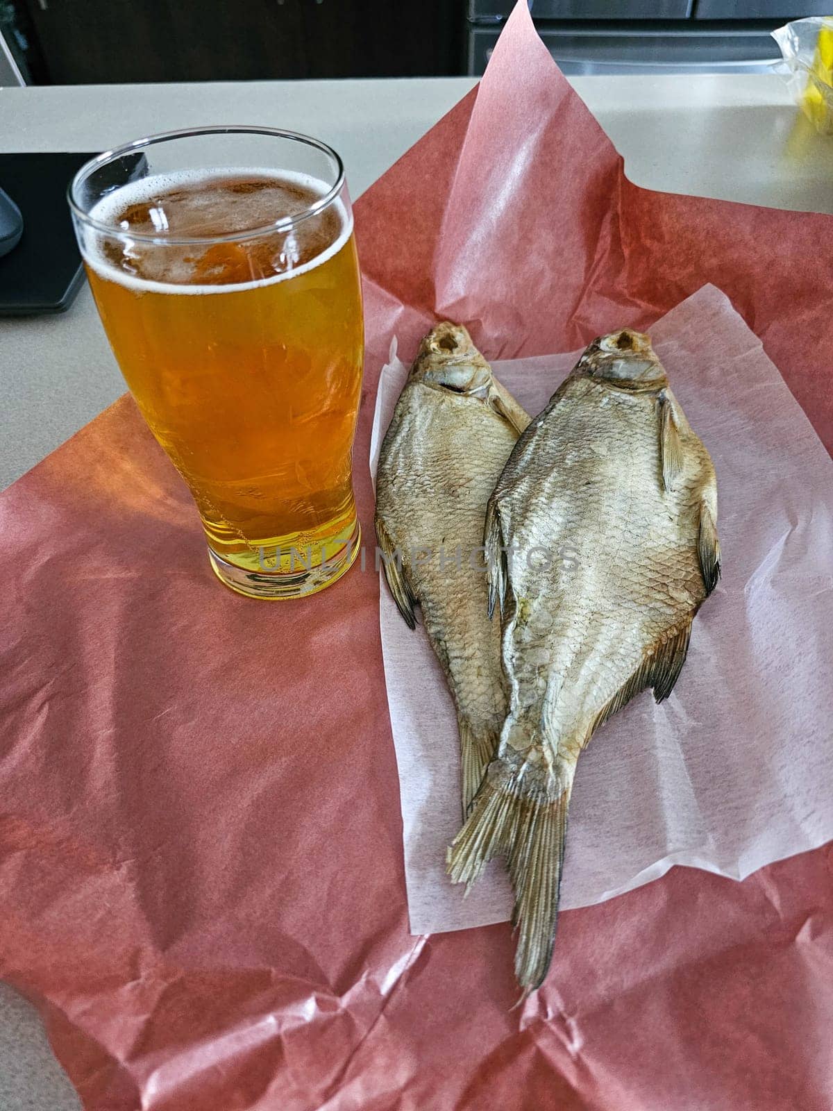 A classic pairing of dried fish and beer, ideal for a casual snack or meal. This still life captures traditional flavors and simple pleasures, perfect for food publications.