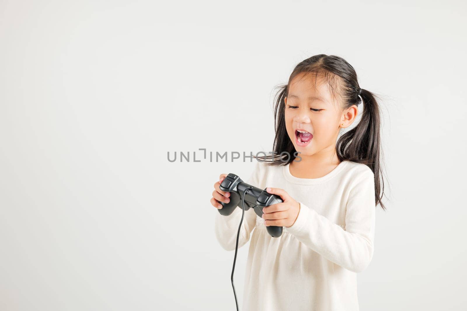 Asian happy portrait young kid girl smile lifestyle games technology holding joystick game playing on hands studio shot isolated white background with copy space, kindergarten child relaxation time