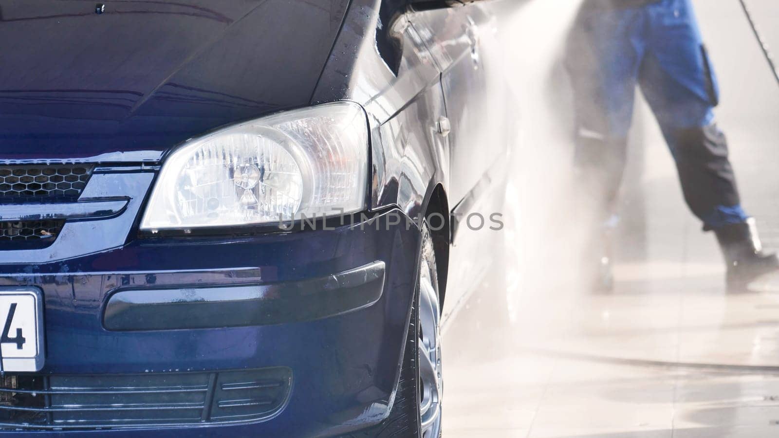 Front of a black car getting washed in an automatic car wash station