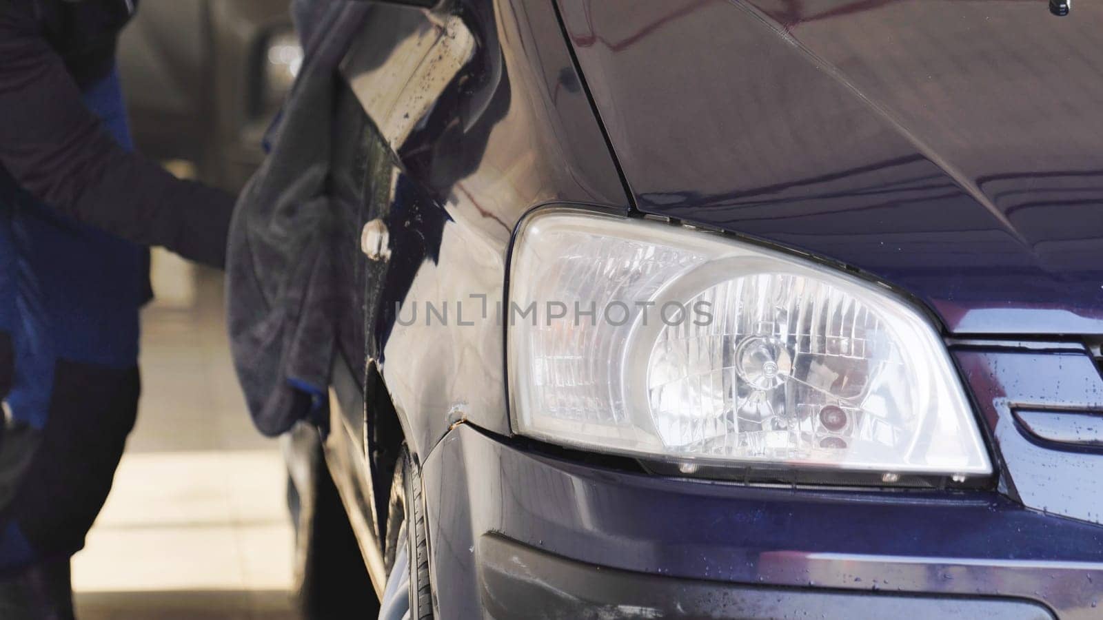 Car wash worker polishing a car with a microfiber cloth, cleaning service concept
