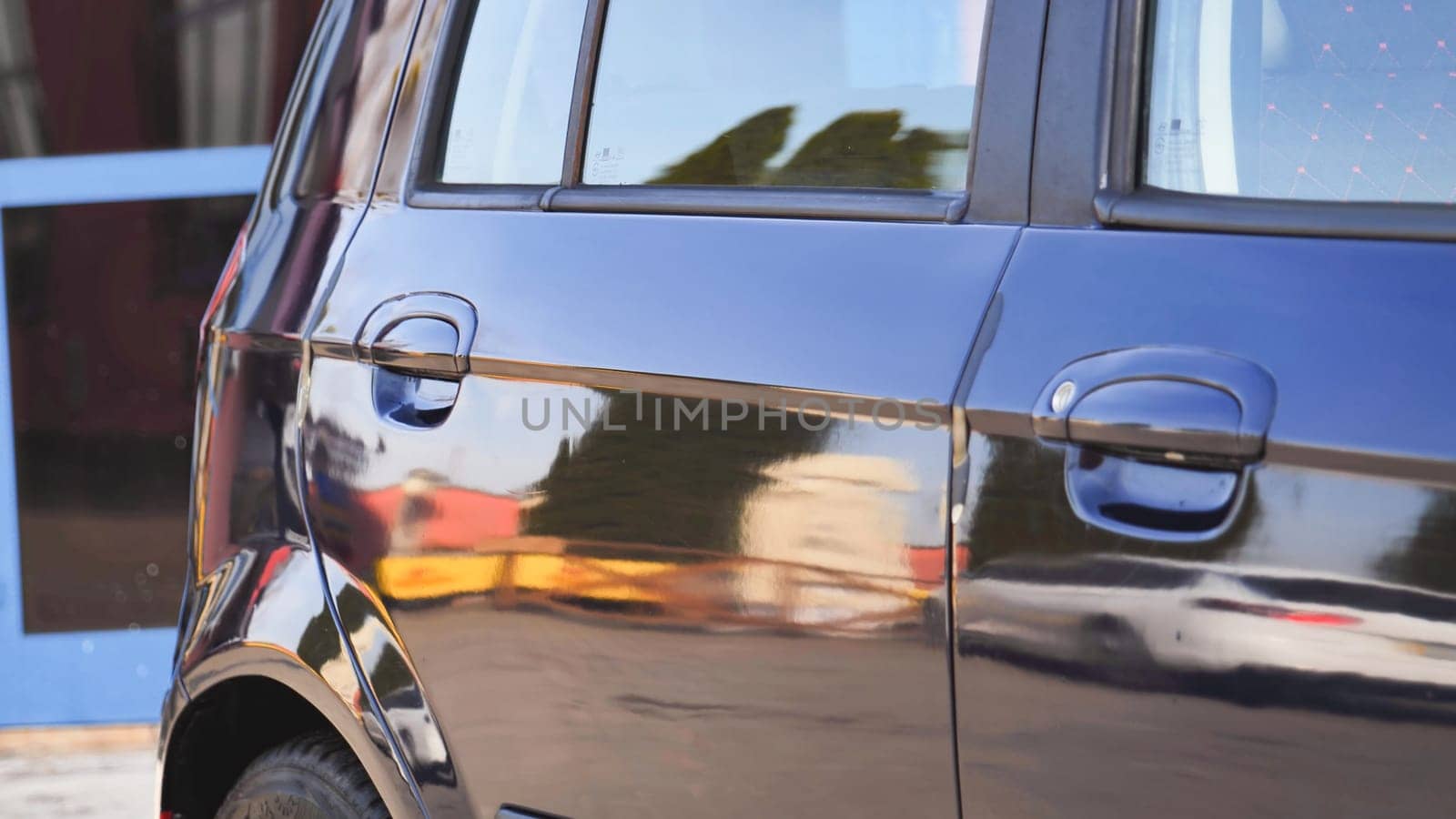 Polished car reflecting surrounding buildings after car wash service