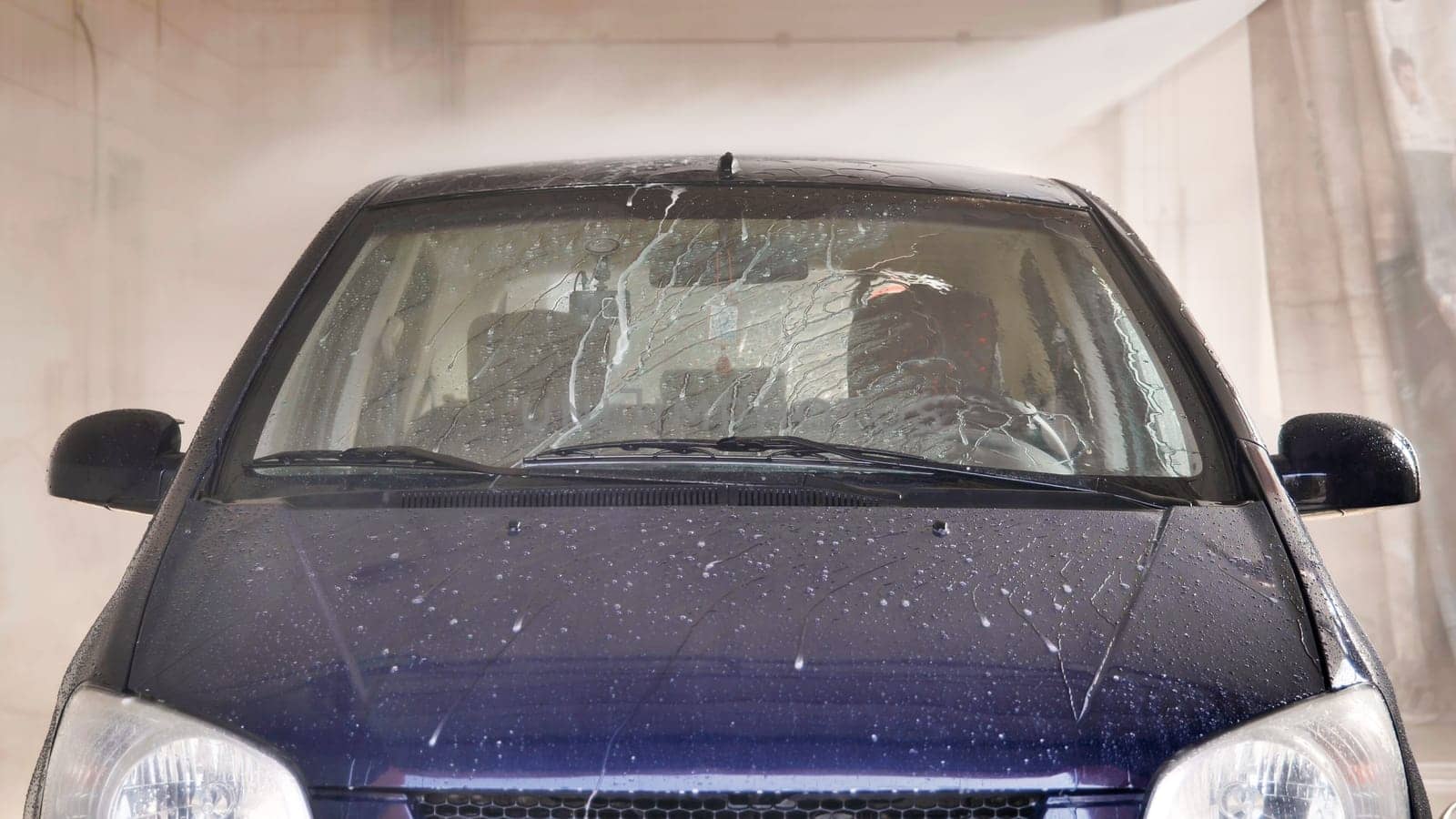 Car going through automatic car wash being sprayed with soap and pressurized water