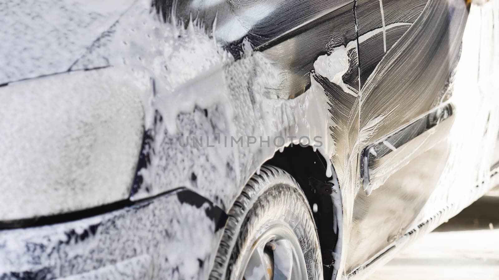 Active foam dripping from a black car during a car wash