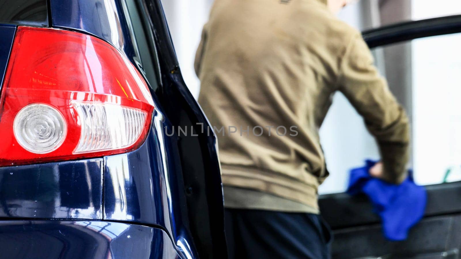 Professional car wash service worker polishing a car window with a microfiber cloth
