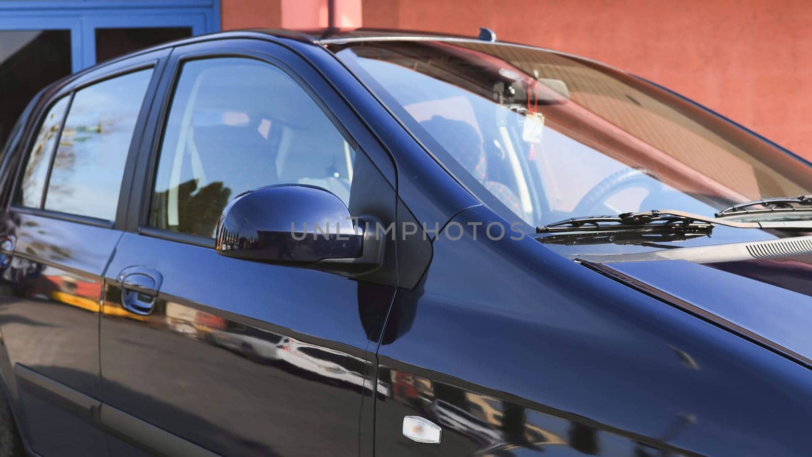 Freshly washed car parked near a car wash, reflecting the surrounding buildings in its polished surface