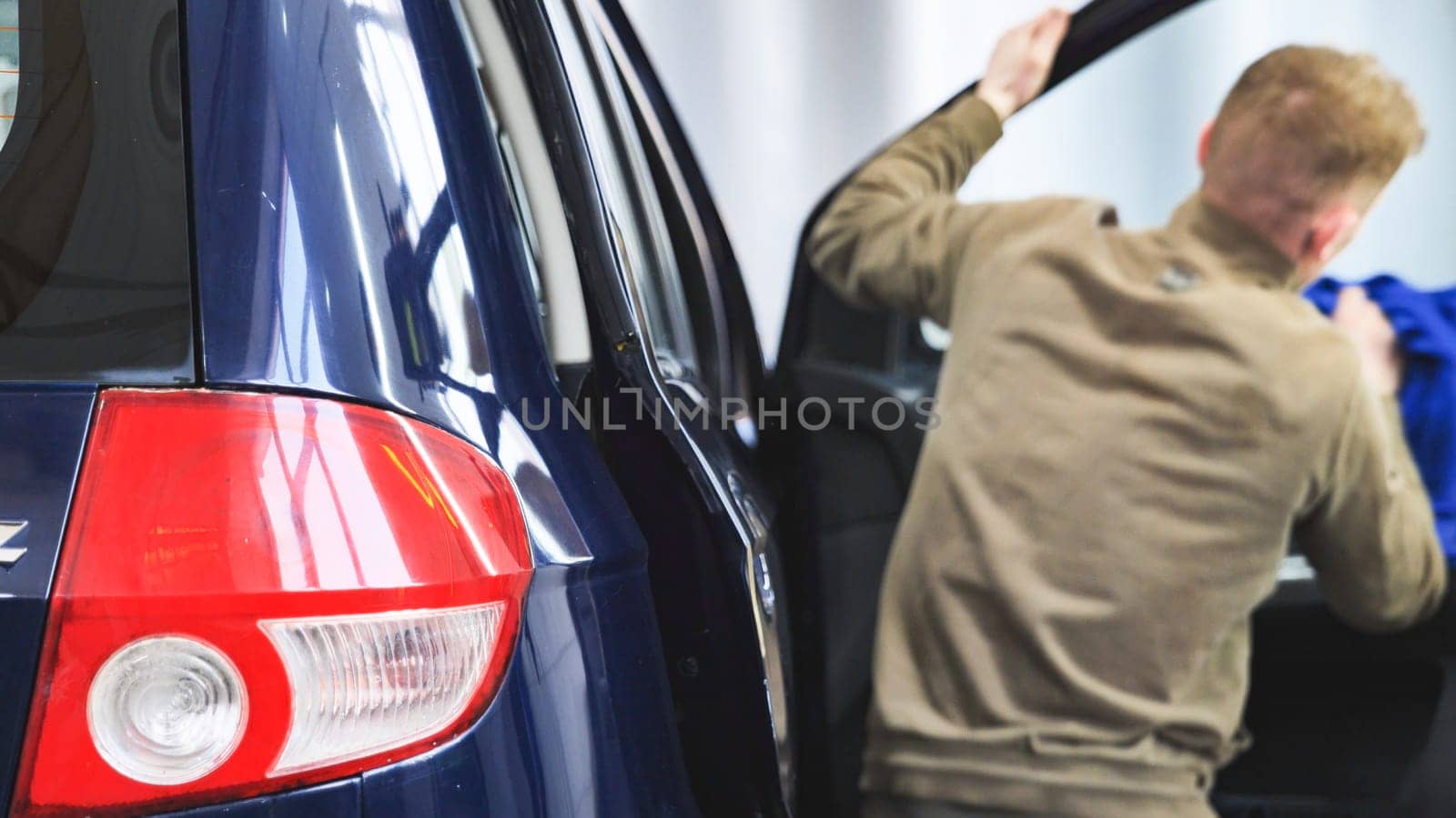 Car wash employee cleaning vehicle interior with microfiber cloth