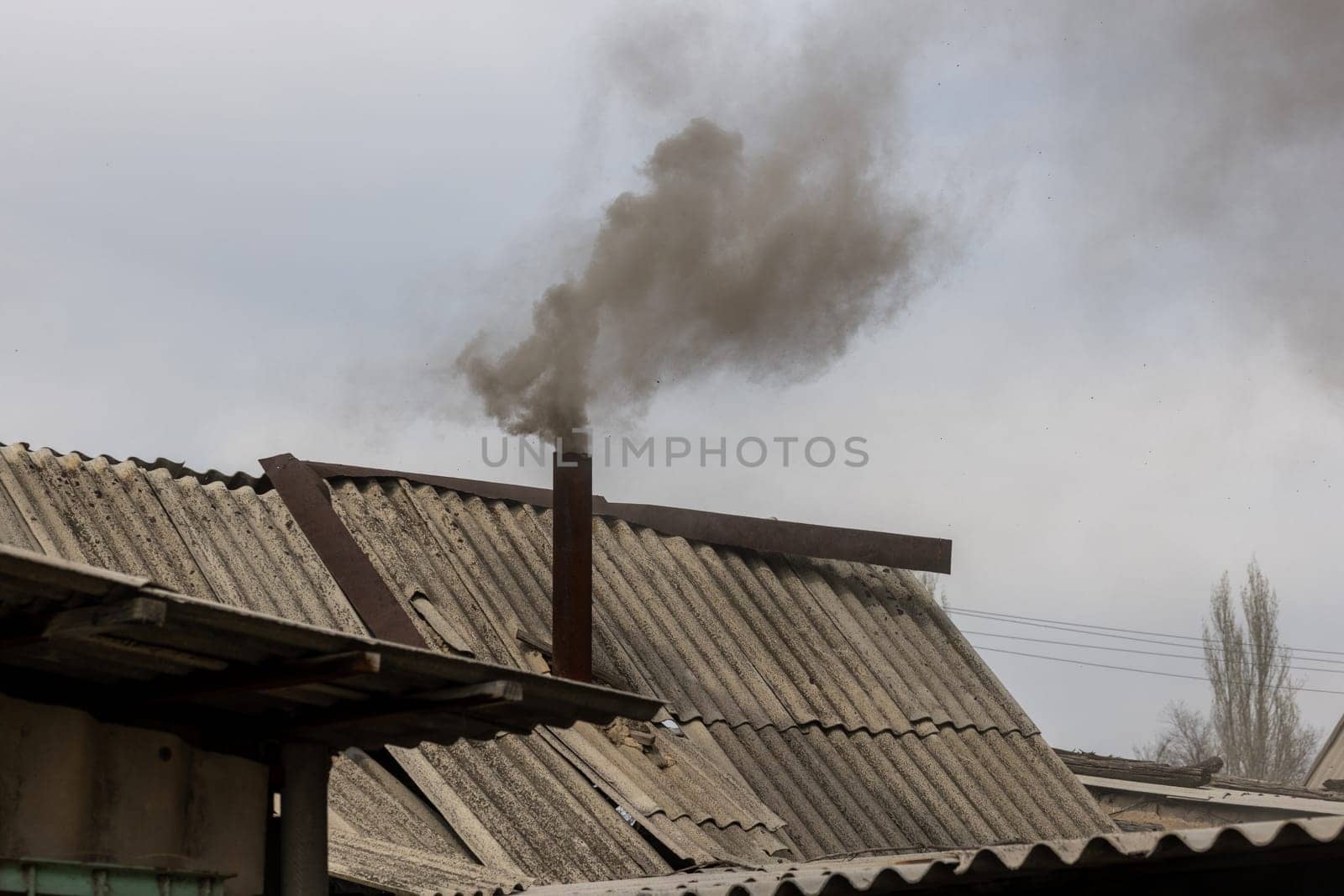 Black smoke coming out from rustic bathhouse chimney steel pipe, the concept of heating with low quality coal or rags.