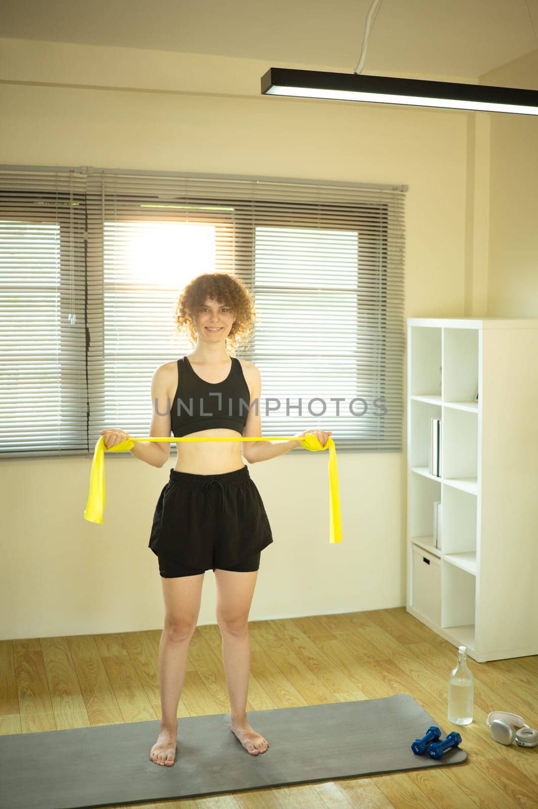 Athletic woman working out with a resistance band in bright living room.