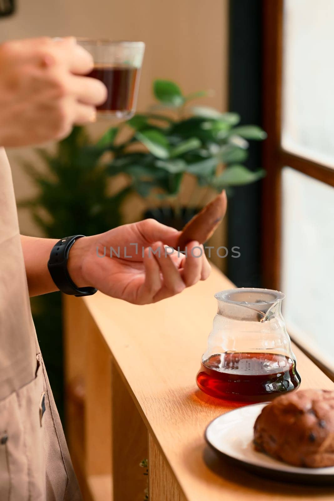 Close up of man brewing coffee with pour over method using a glass dripper in a kitchen.