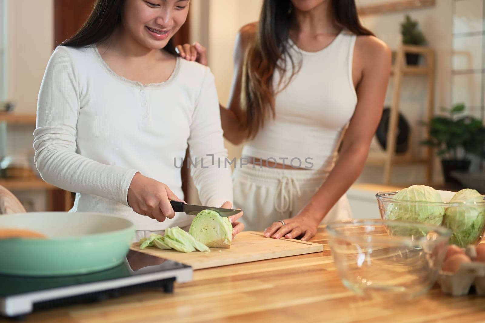 Happy mother and daughter preparing a meal together in the kitchen.