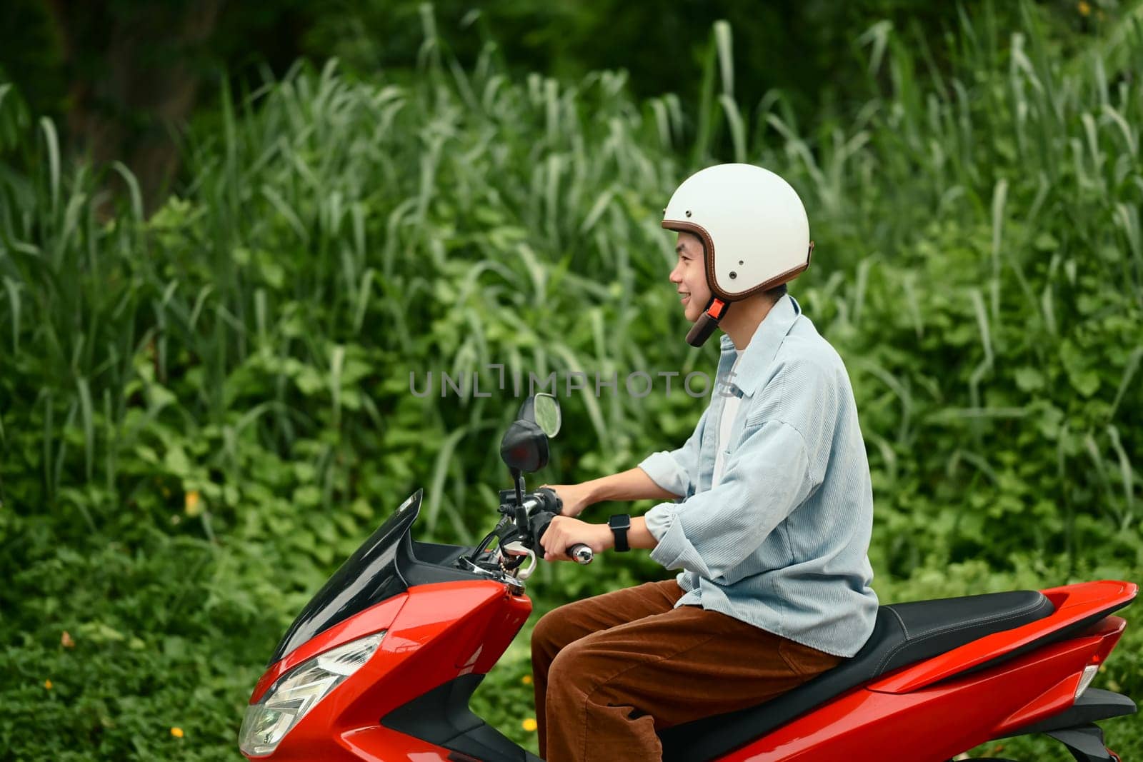 Smiling male motorcyclist enjoying a relaxed ride through a suburban neighborhood..